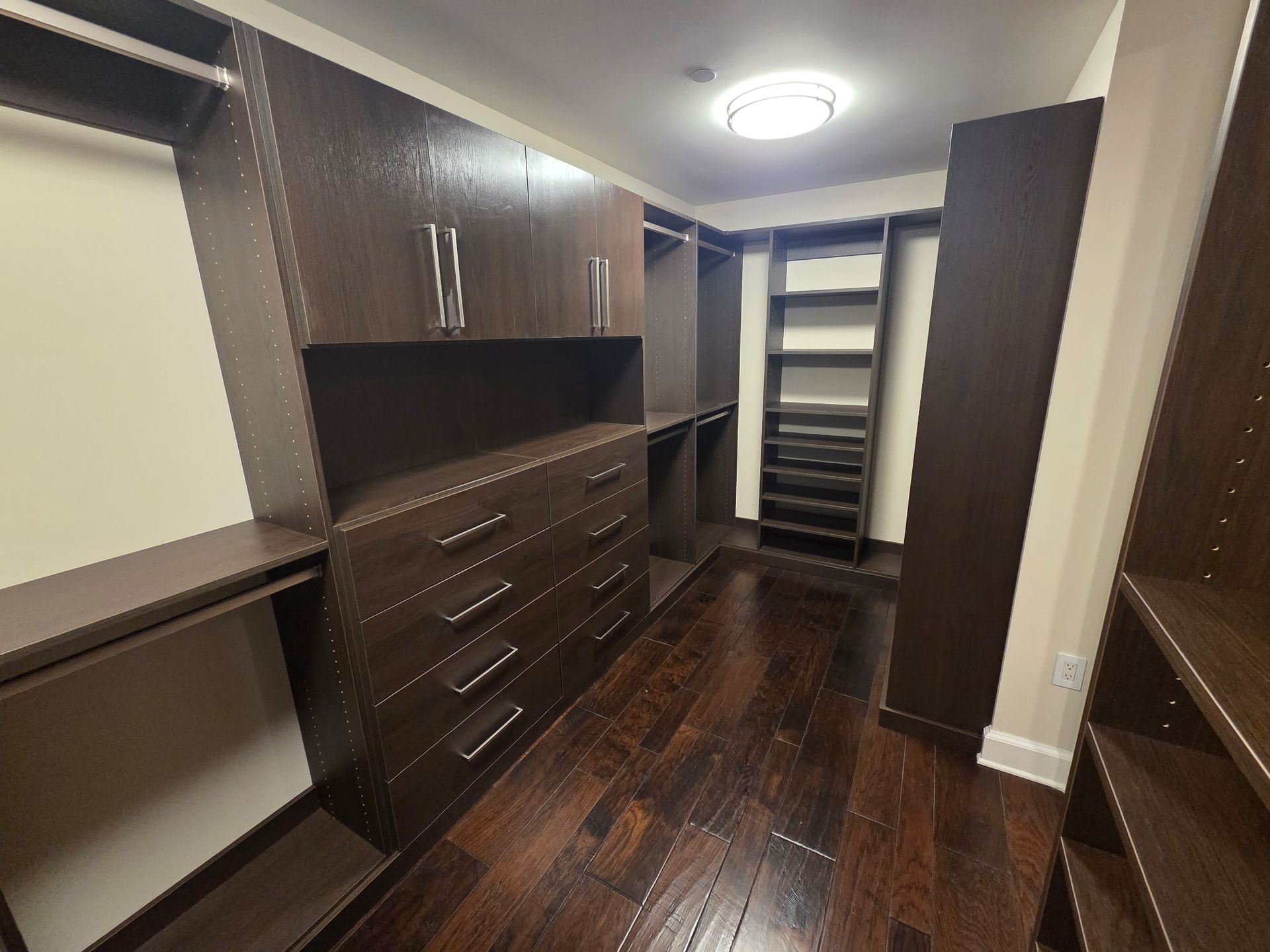 Walk-in closet with dark wood drawers, hanging shelves, and open shelving along one wall