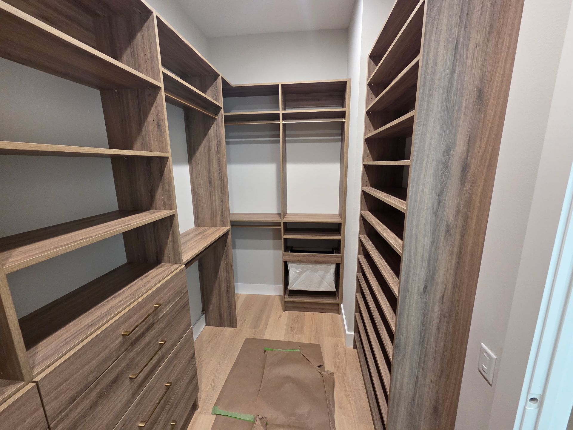 Walk-in closet with wood shelving, drawers, and a built-in shoe rack on the right and back walls.