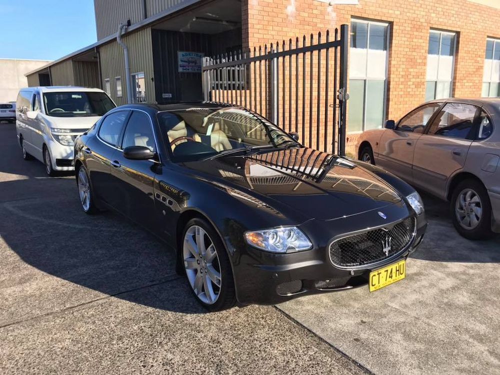 A Black Maserati is Parked in a Parking Lot in Front of a Building — Adettra in Tuncurry, NSW