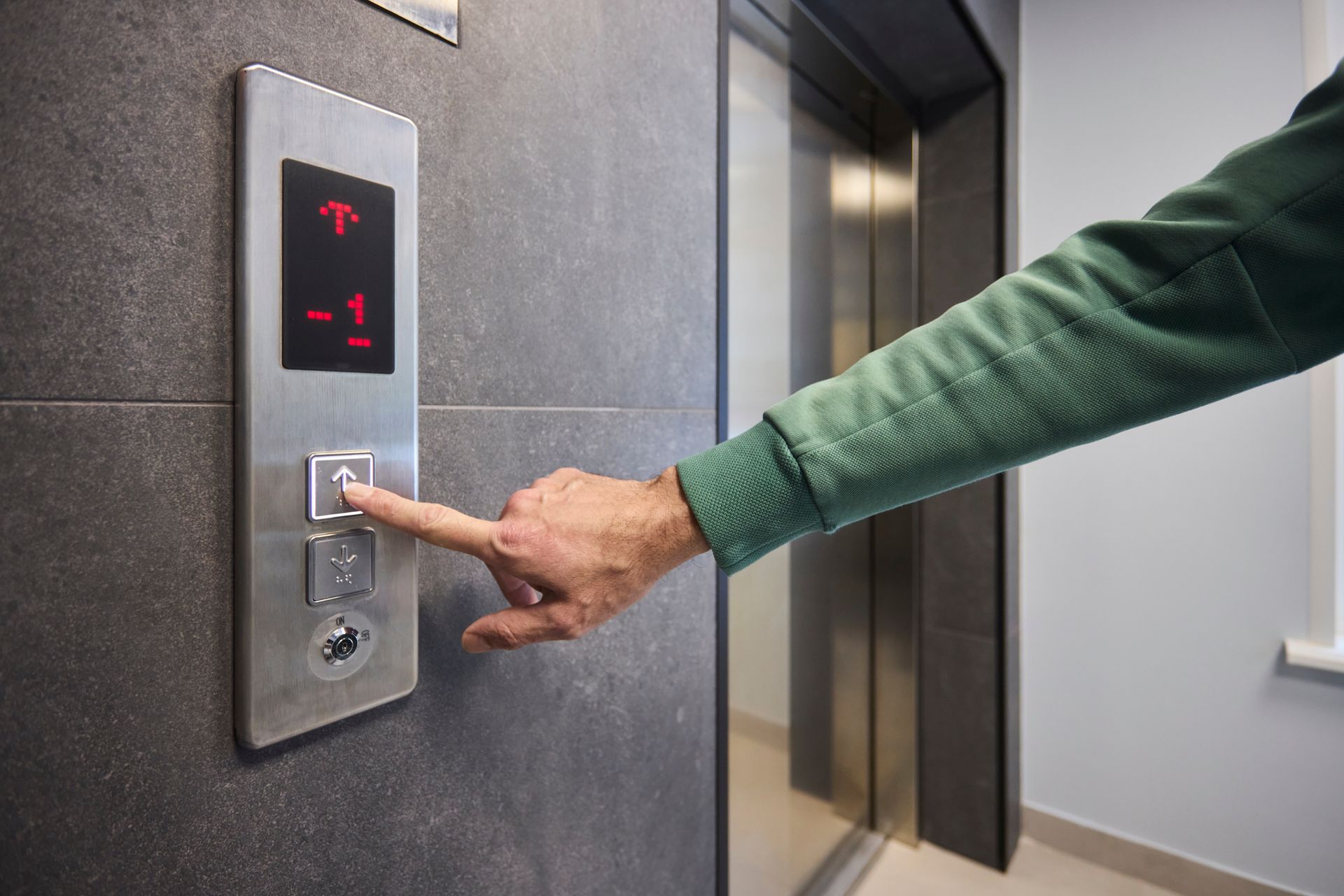 Hand pressing elevator button inside modern building lobby. Hand pressing elevator button inside modern building lobby.
