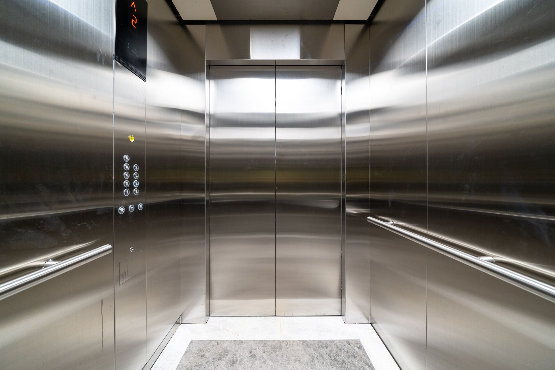 Inside a sleek stainless steel elevator with a digital floor display and controls. Inside a sleek stainless steel elevator with a digital floor display and controls.