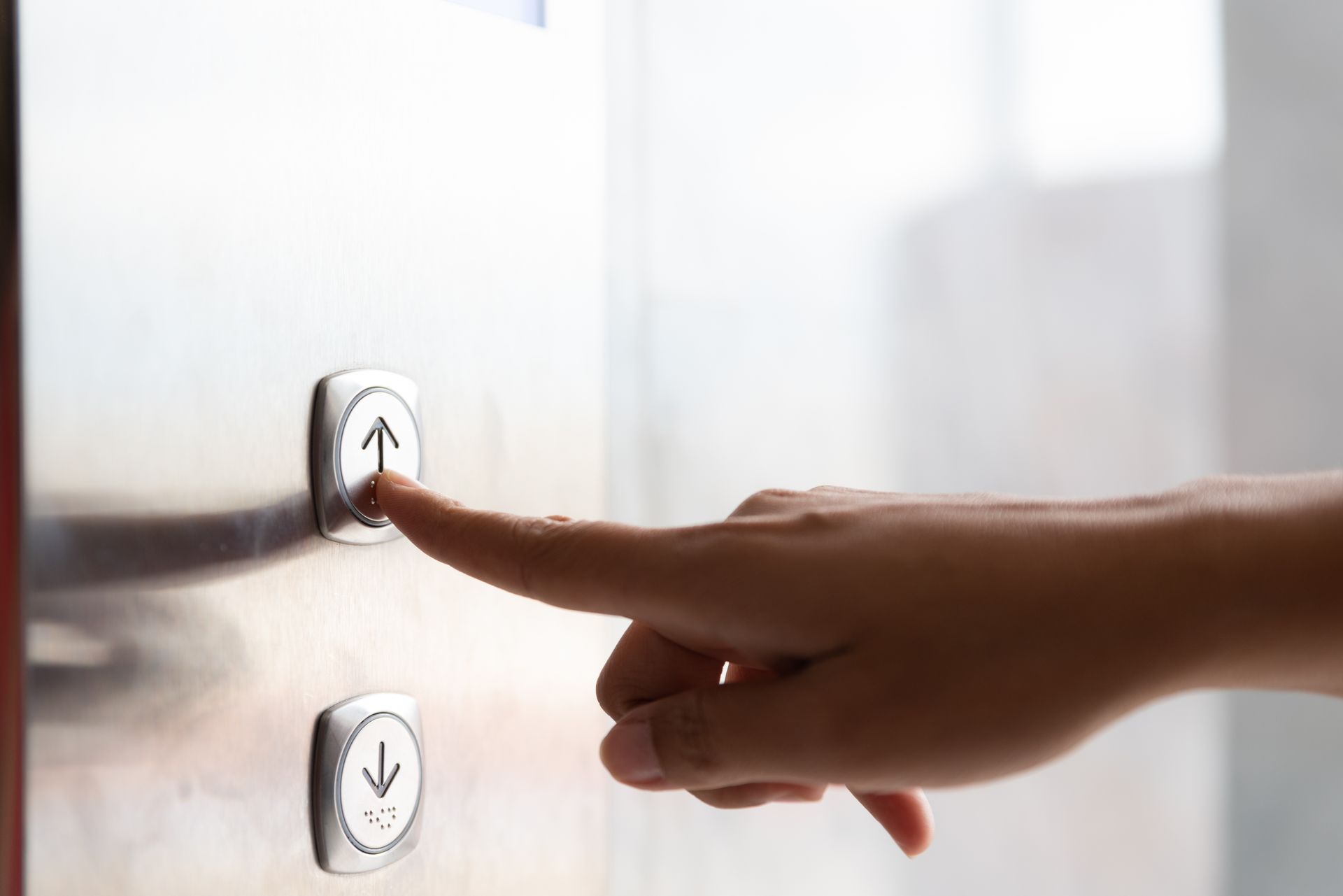 Finger pressing the up button on a wall mounted home elevator control panel. Finger pressing the up button on a wall mounted home elevator control panel.