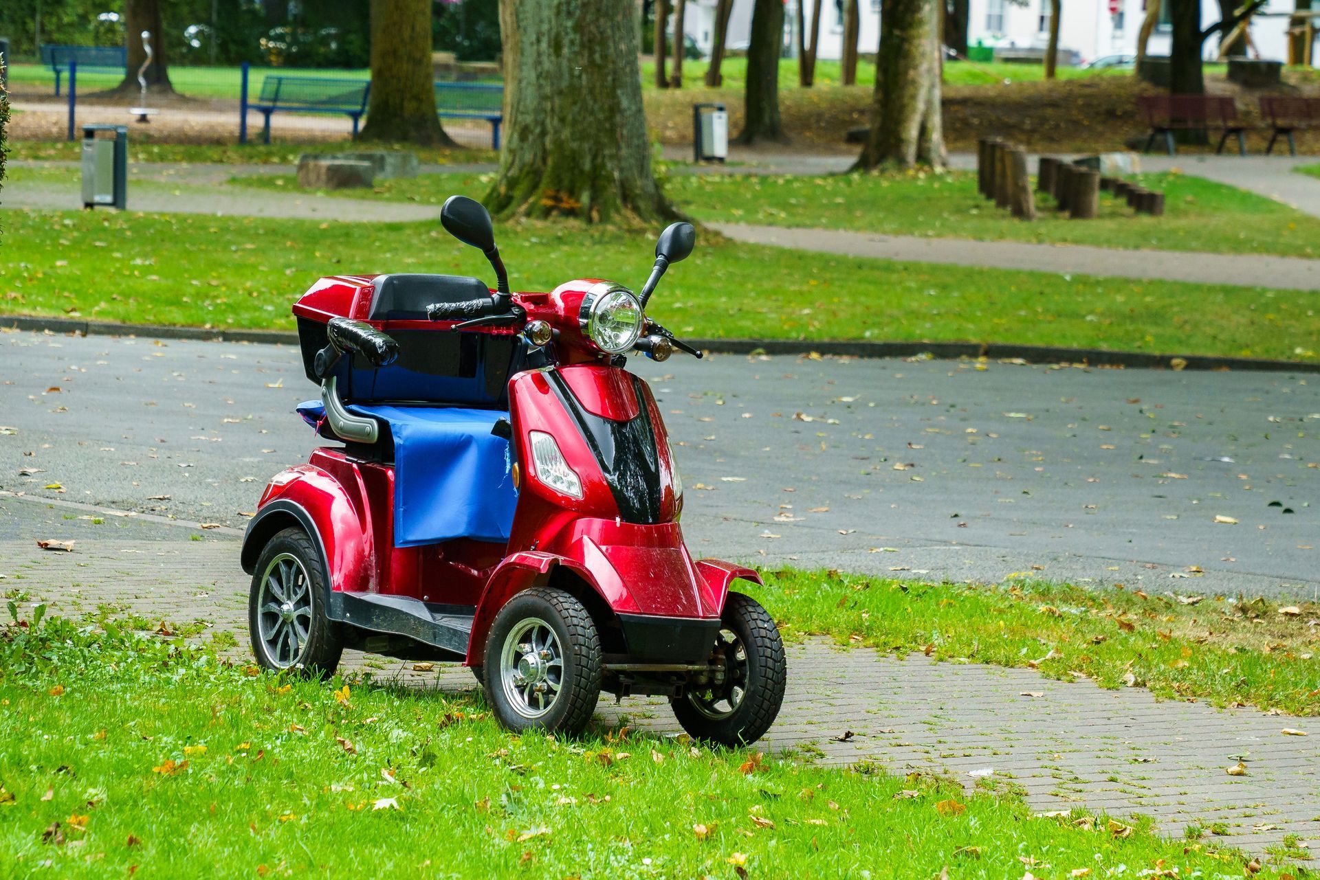 A four-wheeled red motor scooter standing on the side of the road. A four-wheeled red motor scooter standing on the side of the road.