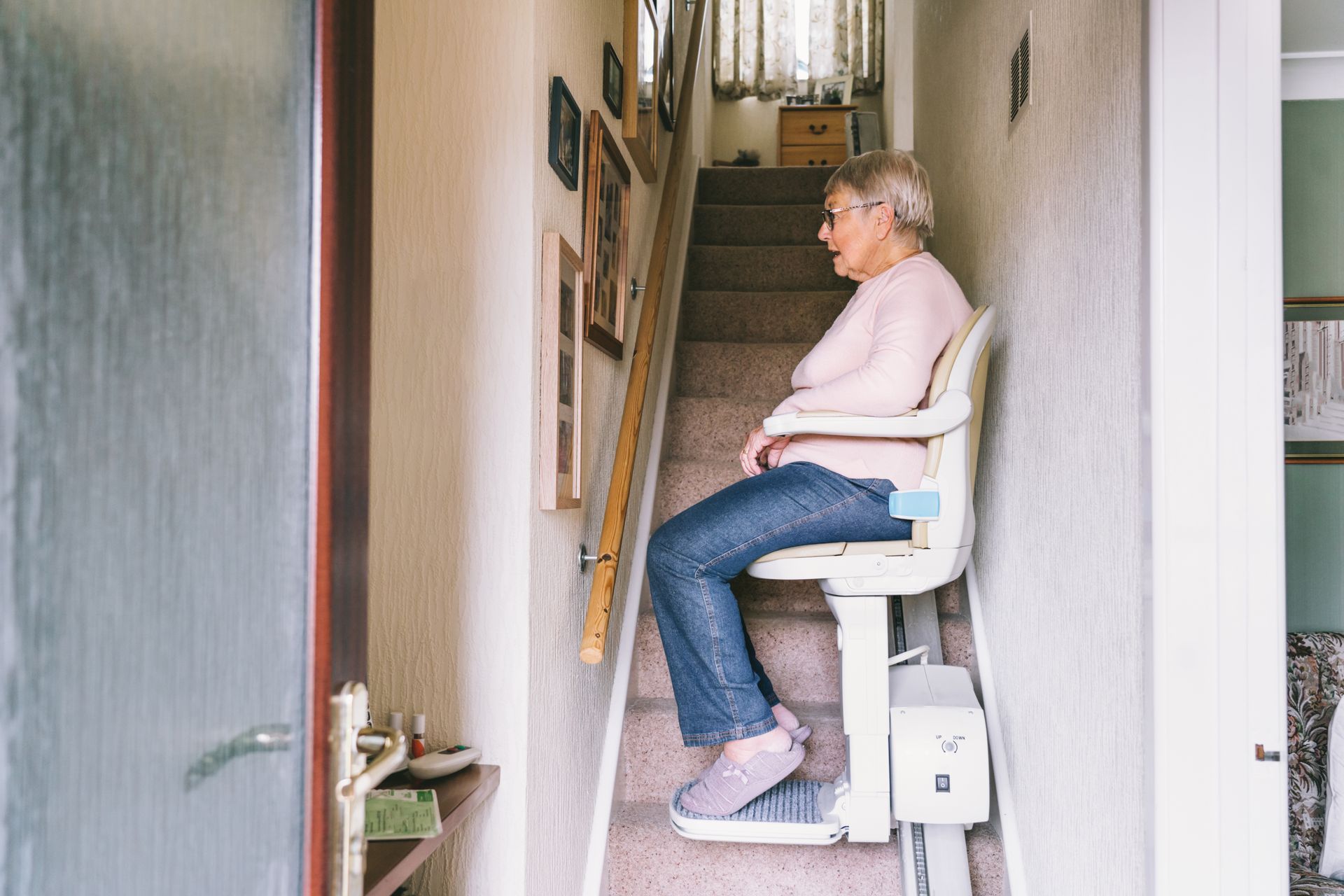 Senior woman using an automatic stair lift on a staircase at her home. Senior woman using an automatic stair lift on a staircase at her home.