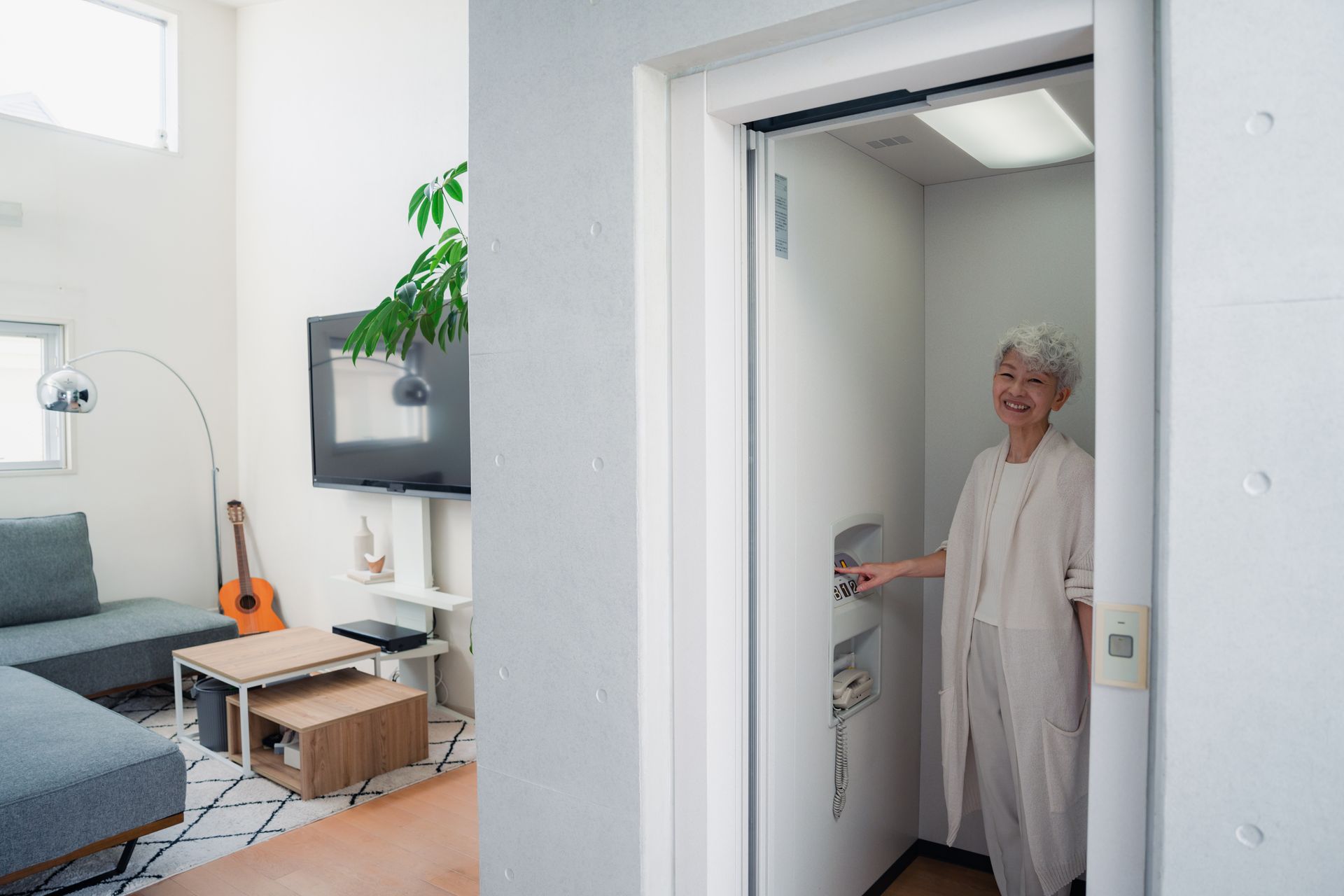 Person standing inside a modern home elevator with open door in a bright living room. Person standing inside a modern home elevator with open door in a bright living room.