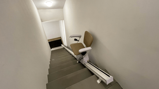 A stair lift is sitting on the bottom of a set of stairs.