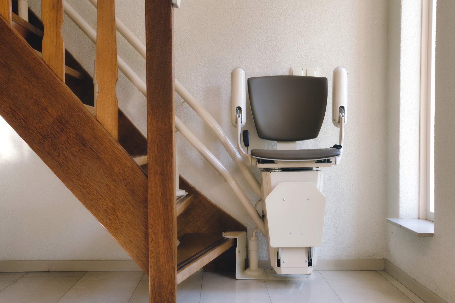 A stair lift is sitting next to a wooden staircase.