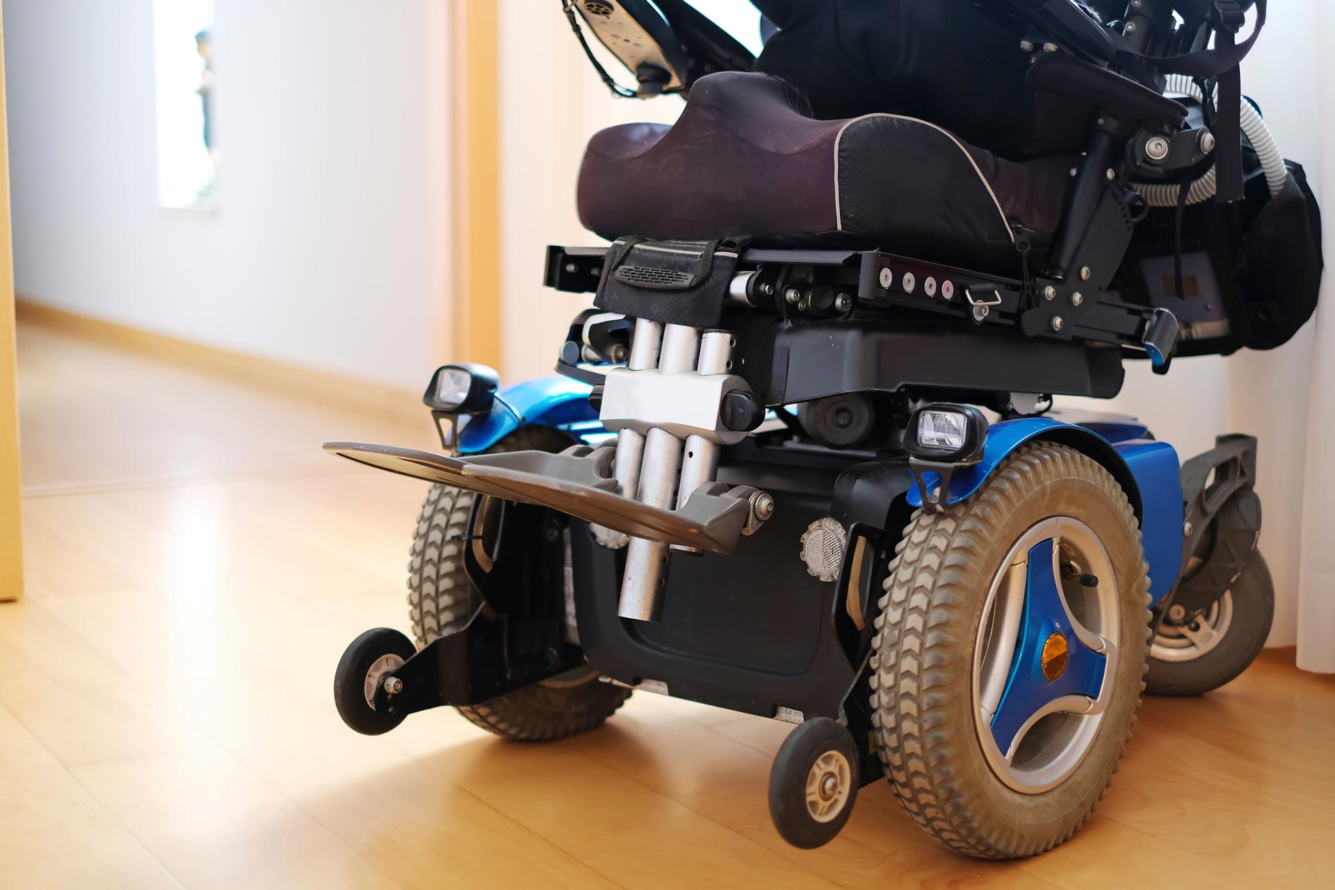 A person in a wheelchair is sitting on a wooden floor