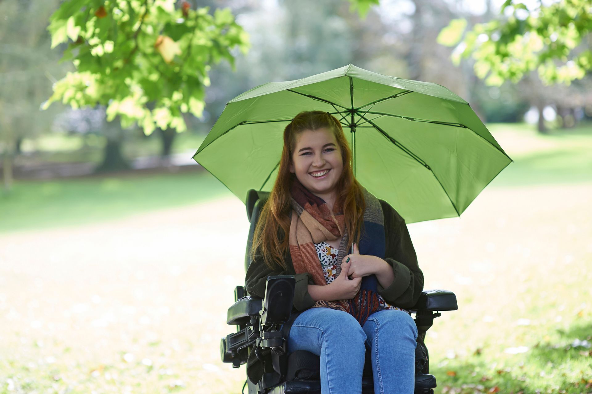 A woman in a wheelchair holding an umbrella, looking to find a motor scooter dealer for mobility. A woman in a wheelchair holding an umbrella, looking to find a motor scooter dealer for mobility.