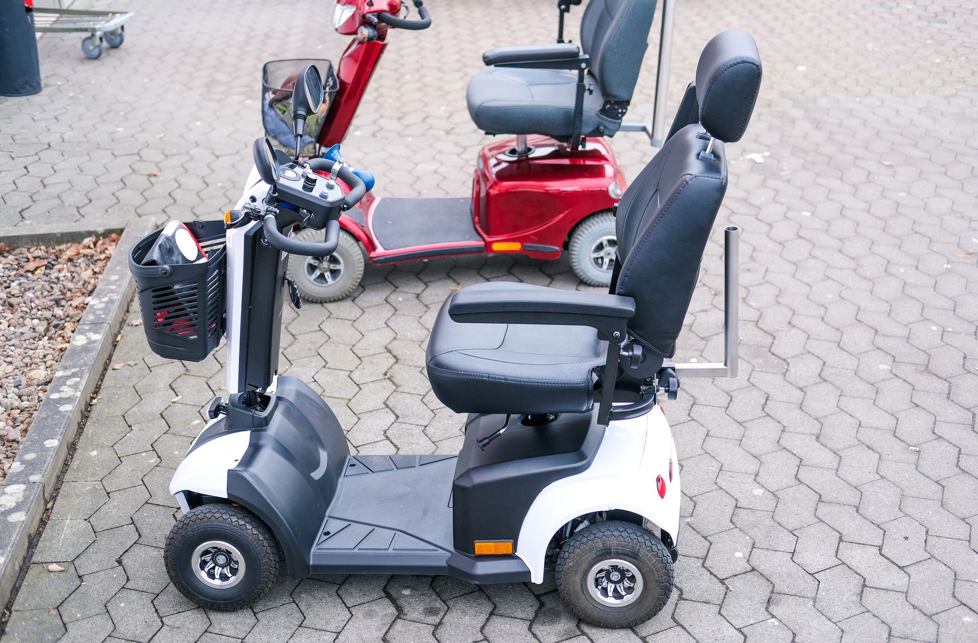Two four-wheel mobility scooters parked on pavement
