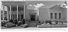 A grayscale building with columns, steps, and windows.