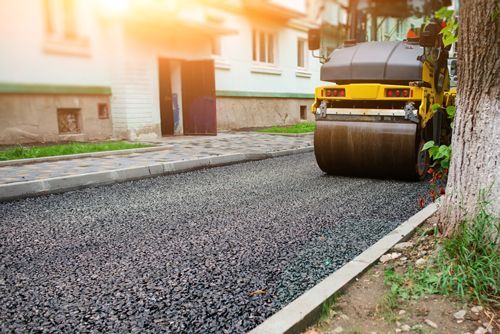 Asphalt resurfacing contractor roller pressing asphalt on a road. Clio, MI - Chippewa Asphalt Paving