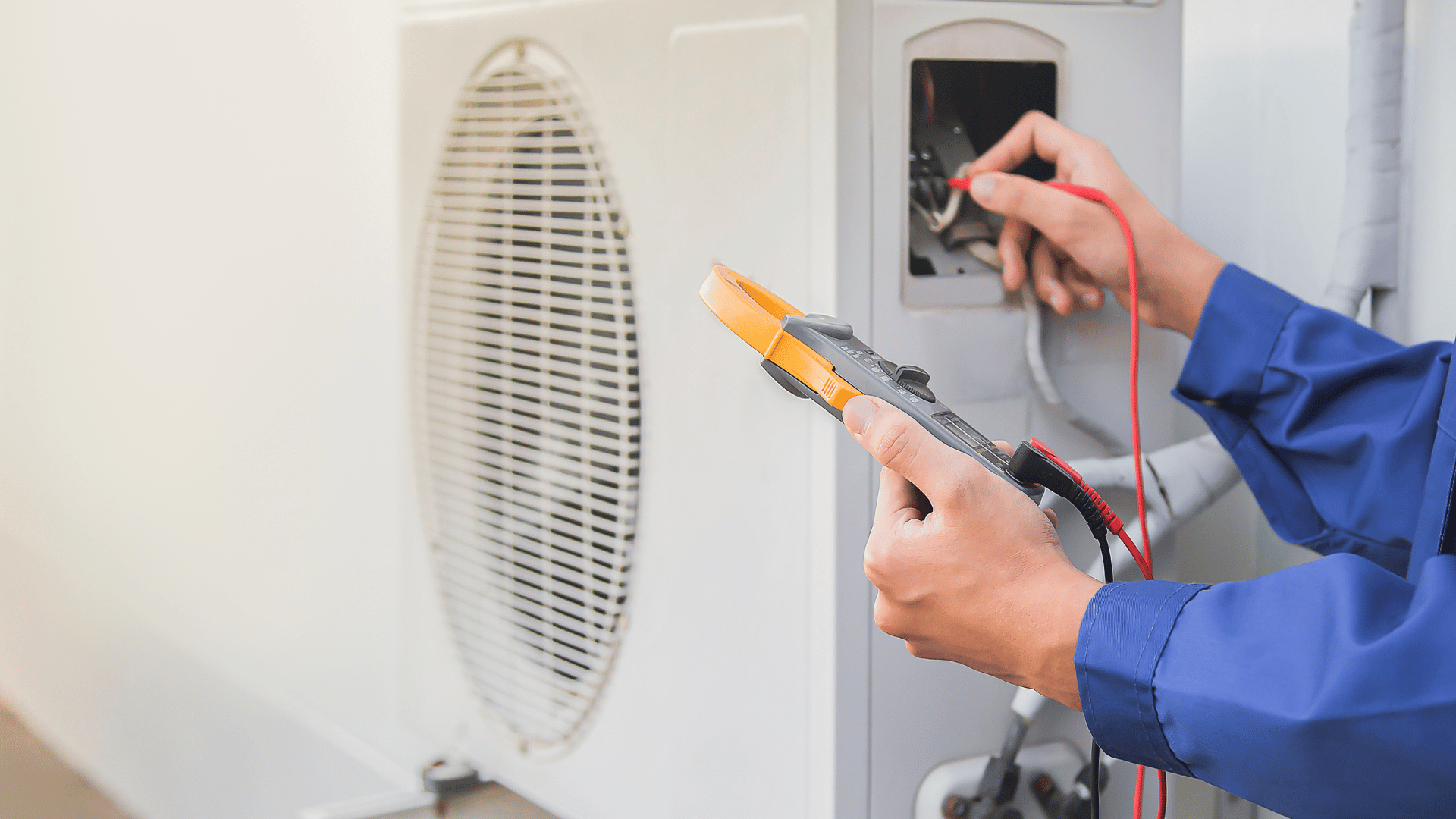 A man is using a multimeter to check the voltage of an air conditioner.
