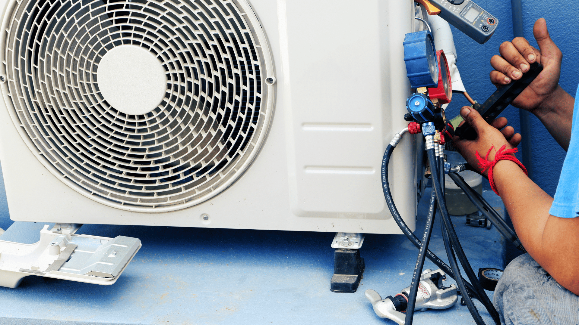 A man is working on an air conditioner outside of a building.