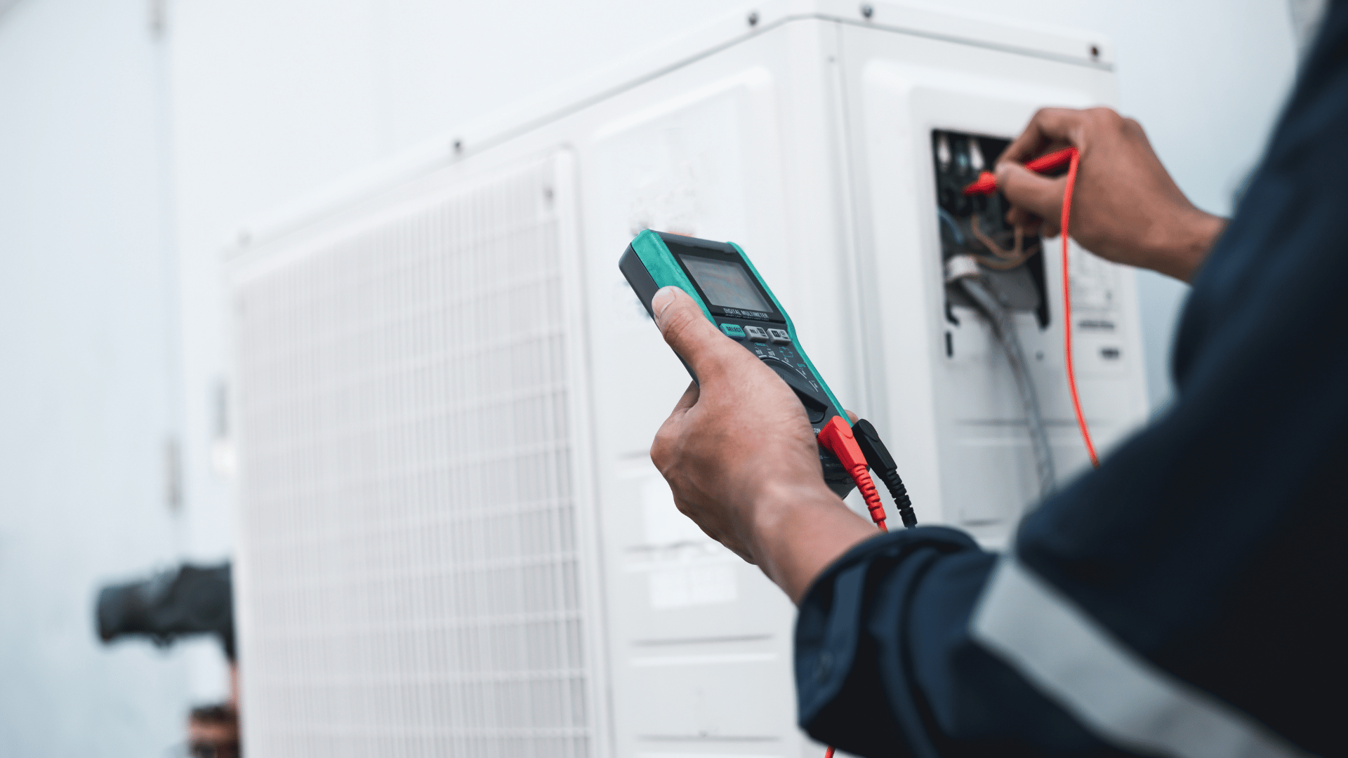 A man is using a digital multimeter to test an air conditioner.