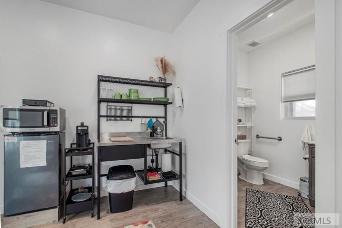 Modern kitchen and dining area with white countertops, stainless fridge, and a wall-mounted TV.