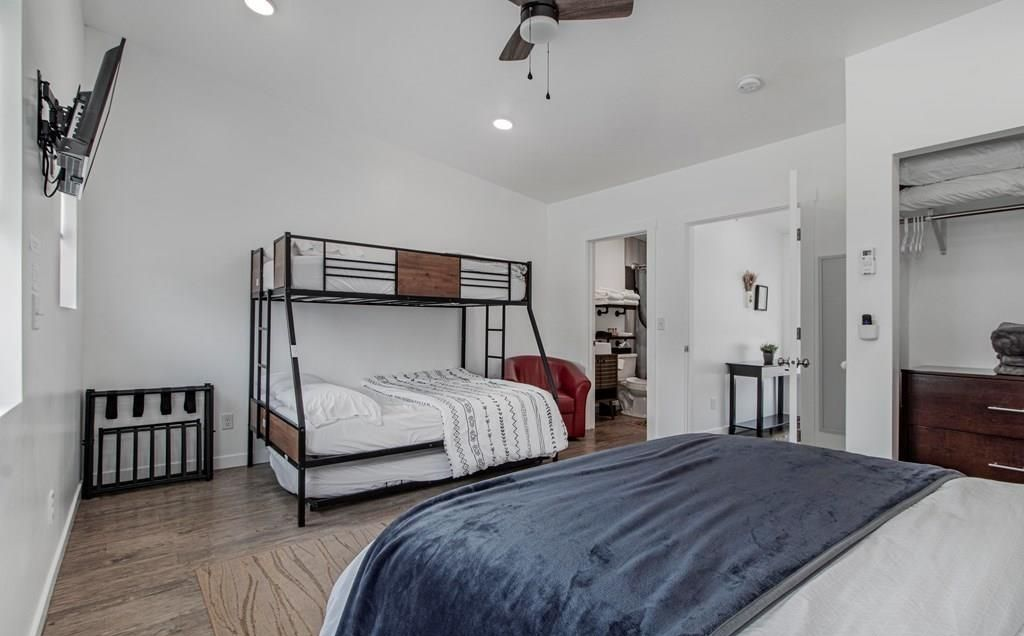 Bright minimalist bedroom with bunk bed, gray walls, wood floor, and dark blue comforter in foreground