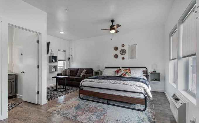 Bright bedroom with a bed, couch, rug, and large windows.