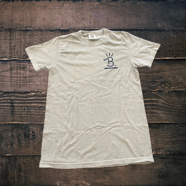 Beige Buck’s Cattle & Beef T-shirt laid flat on a wooden background