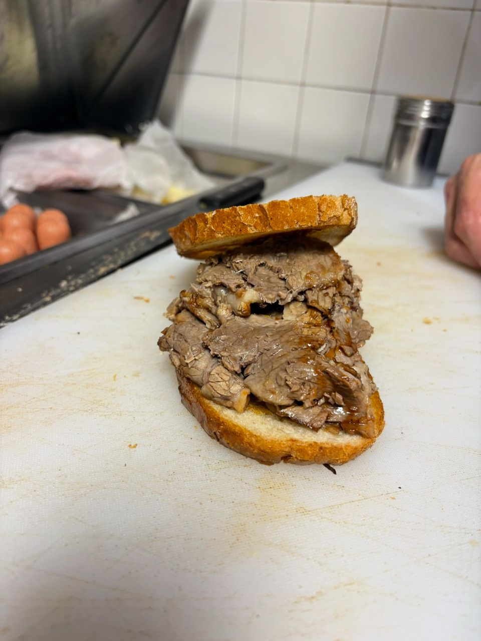 Sandwich with sliced meat on toasted bread, on a cutting board.