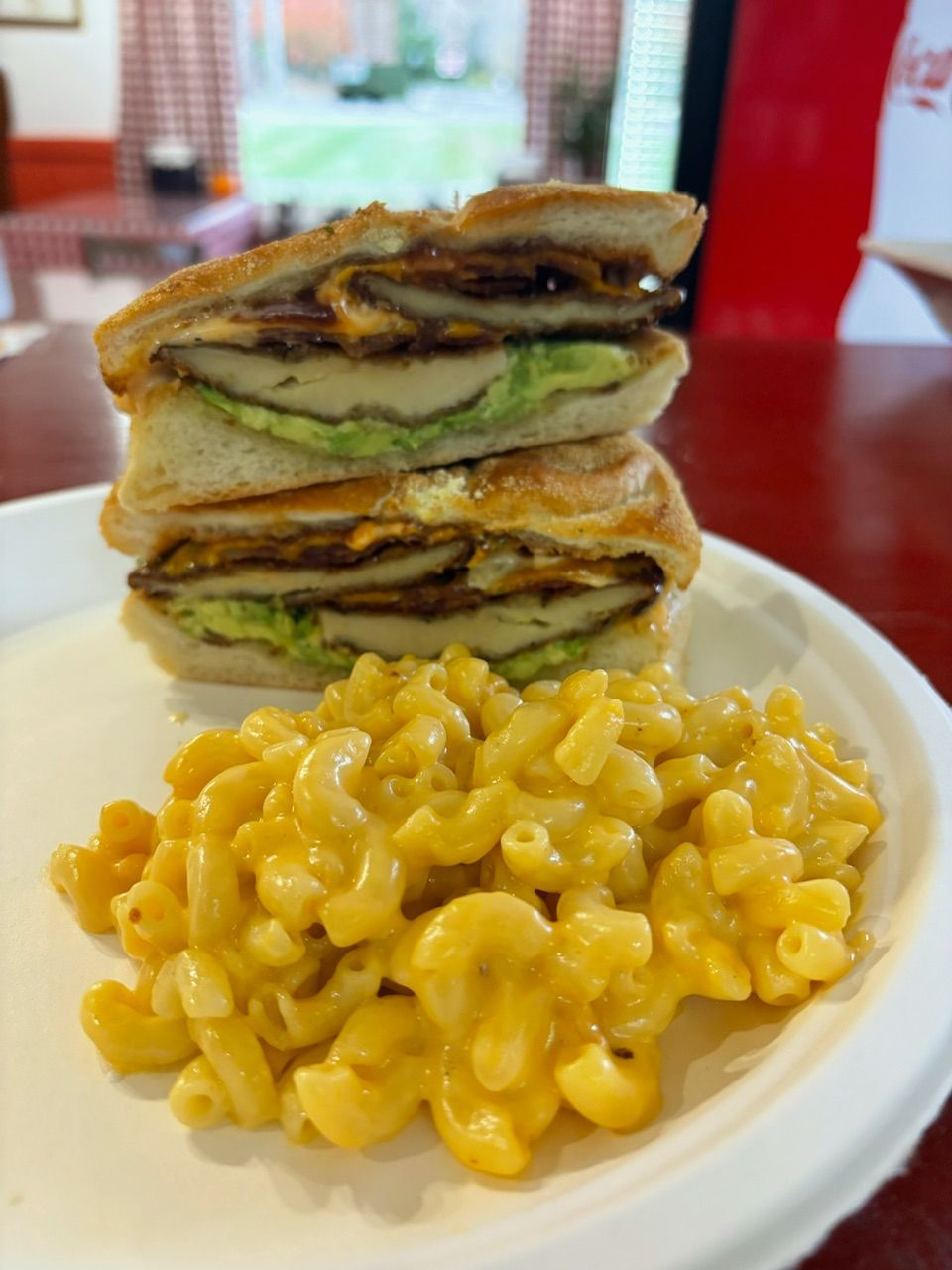 Sandwich with avocado and mac and cheese on a white plate.