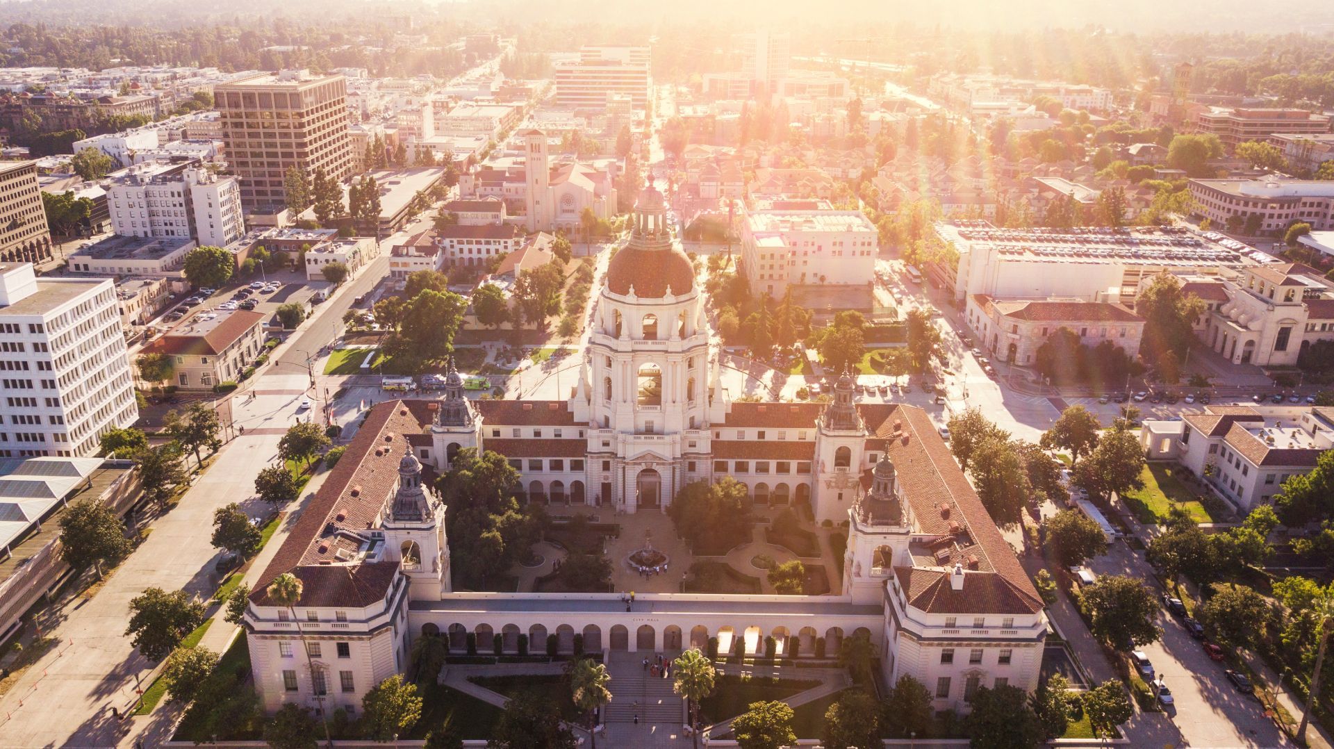 Aerial view of a historic cathedral and surrounding city streets at sunset with warm golden light.