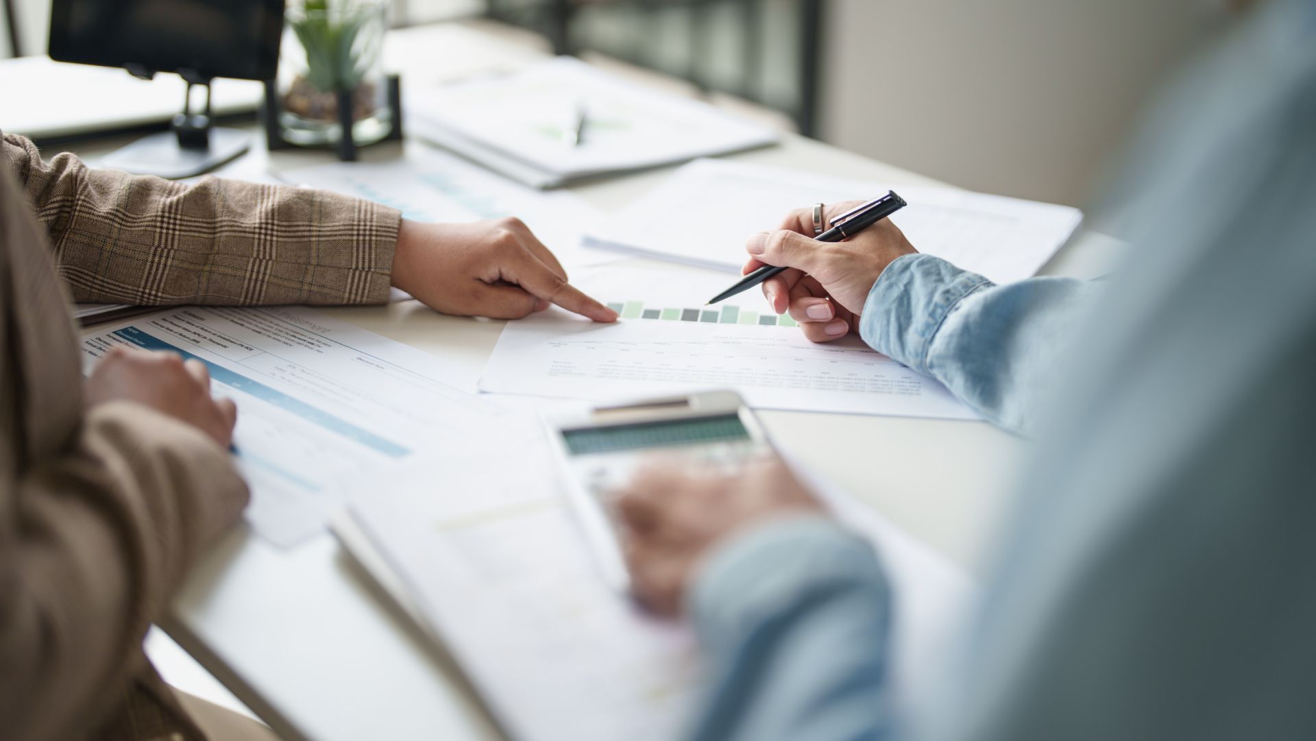 Hands pointing at charts and documents during a meeting at a desk