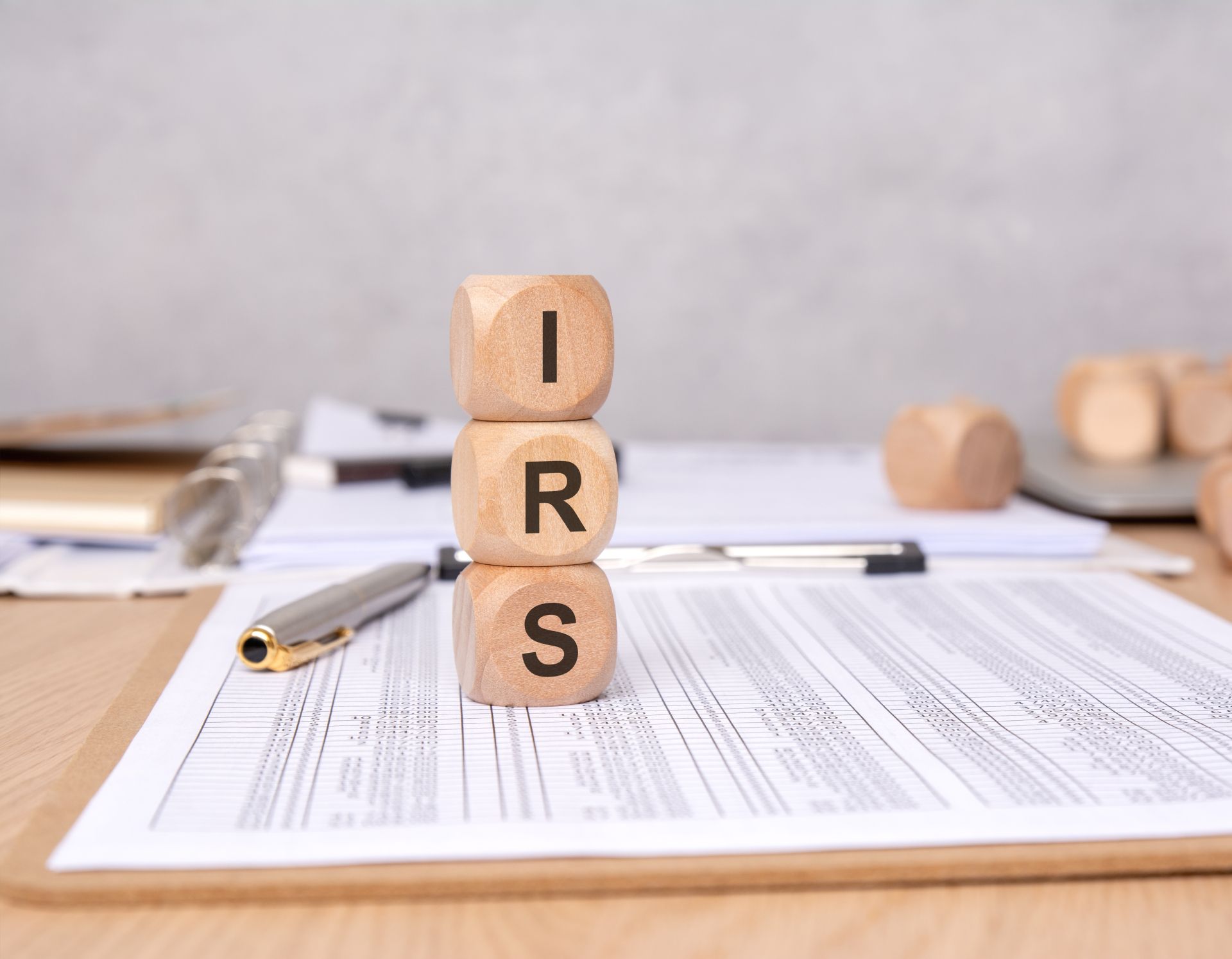 Wooden blocks spelling IRS on financial paperwork with a pen on a desk