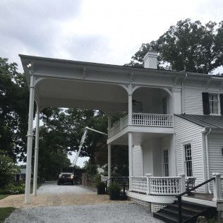 White house with a covered driveway, two-story porch, and a gravel driveway.