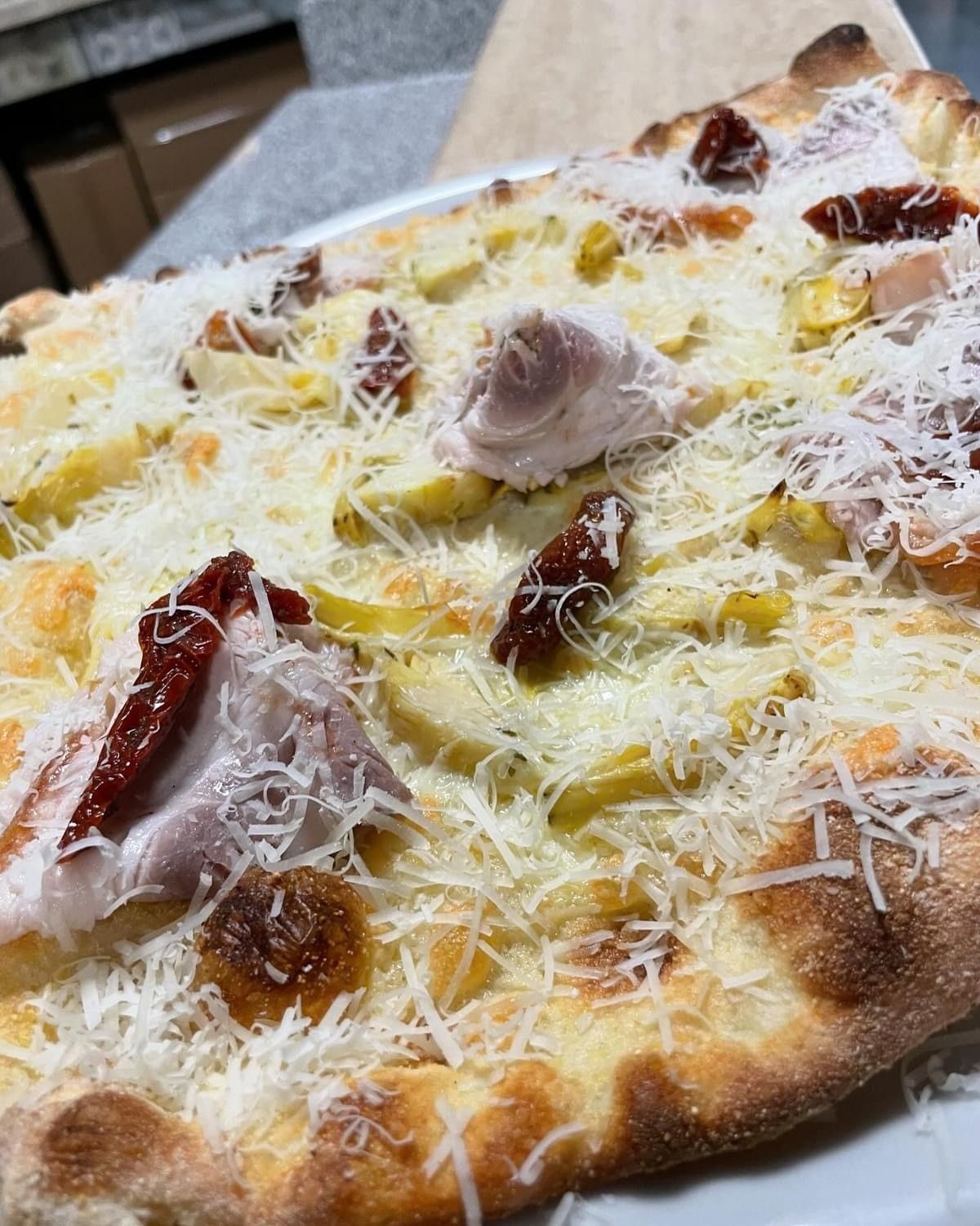 Una pizza con tanti condimenti è servita su un piatto bianco.