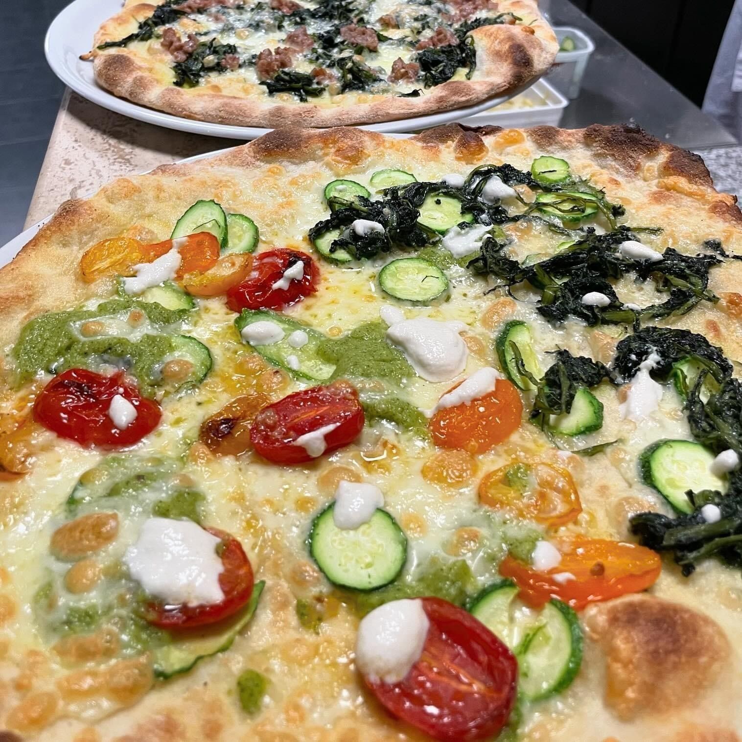Due pizze con condimenti diversi sono appoggiate su un tavolo.