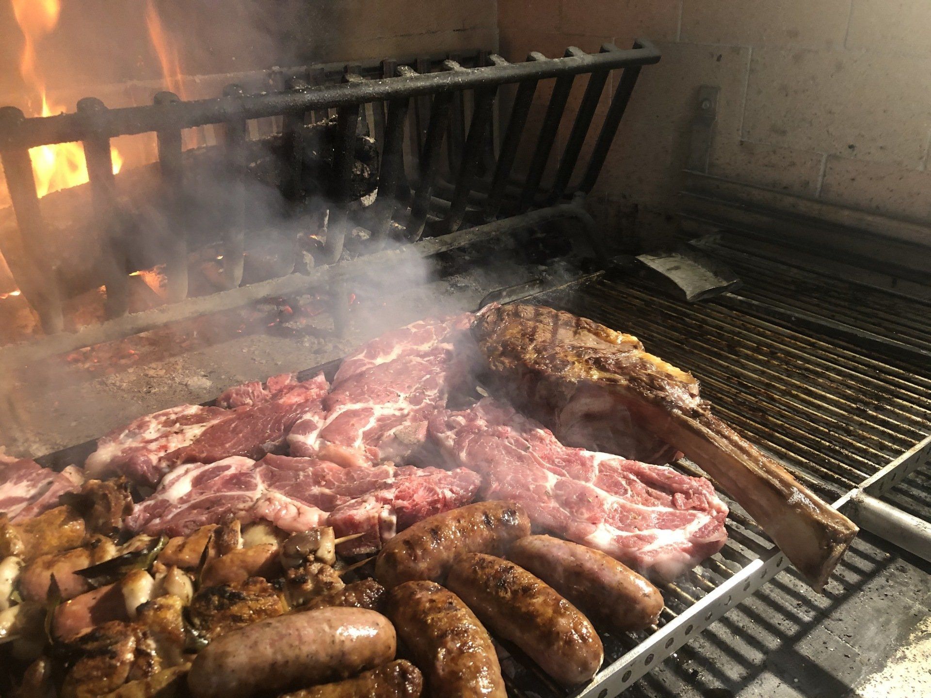 Un mucchio di carne e salsicce stanno cuocendo su una griglia.