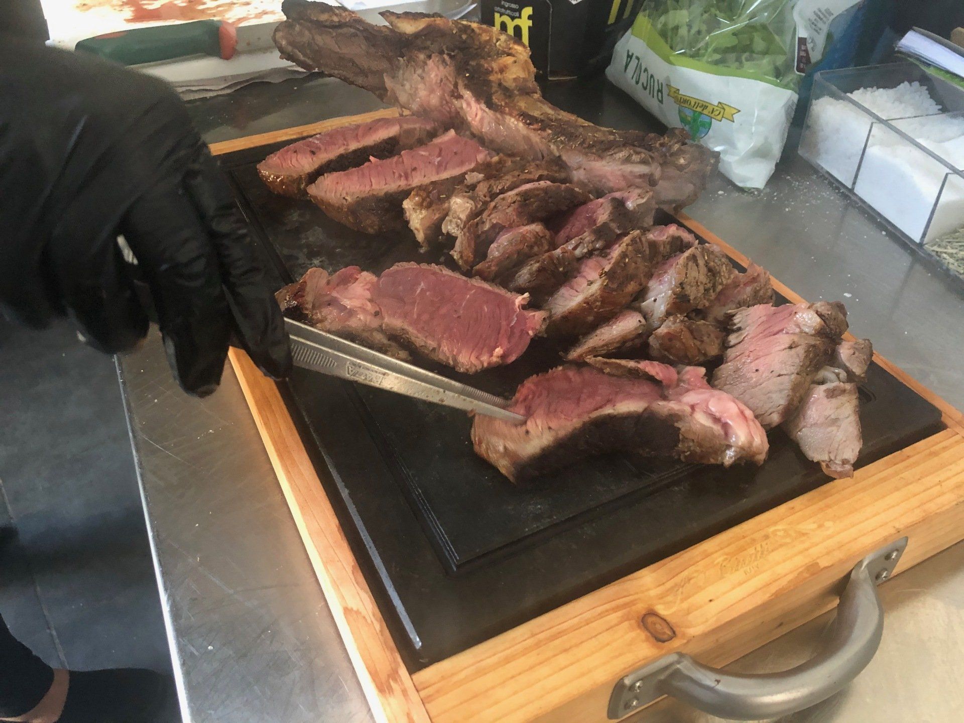 Una persona sta tagliando un grosso pezzo di carne su un tagliere.