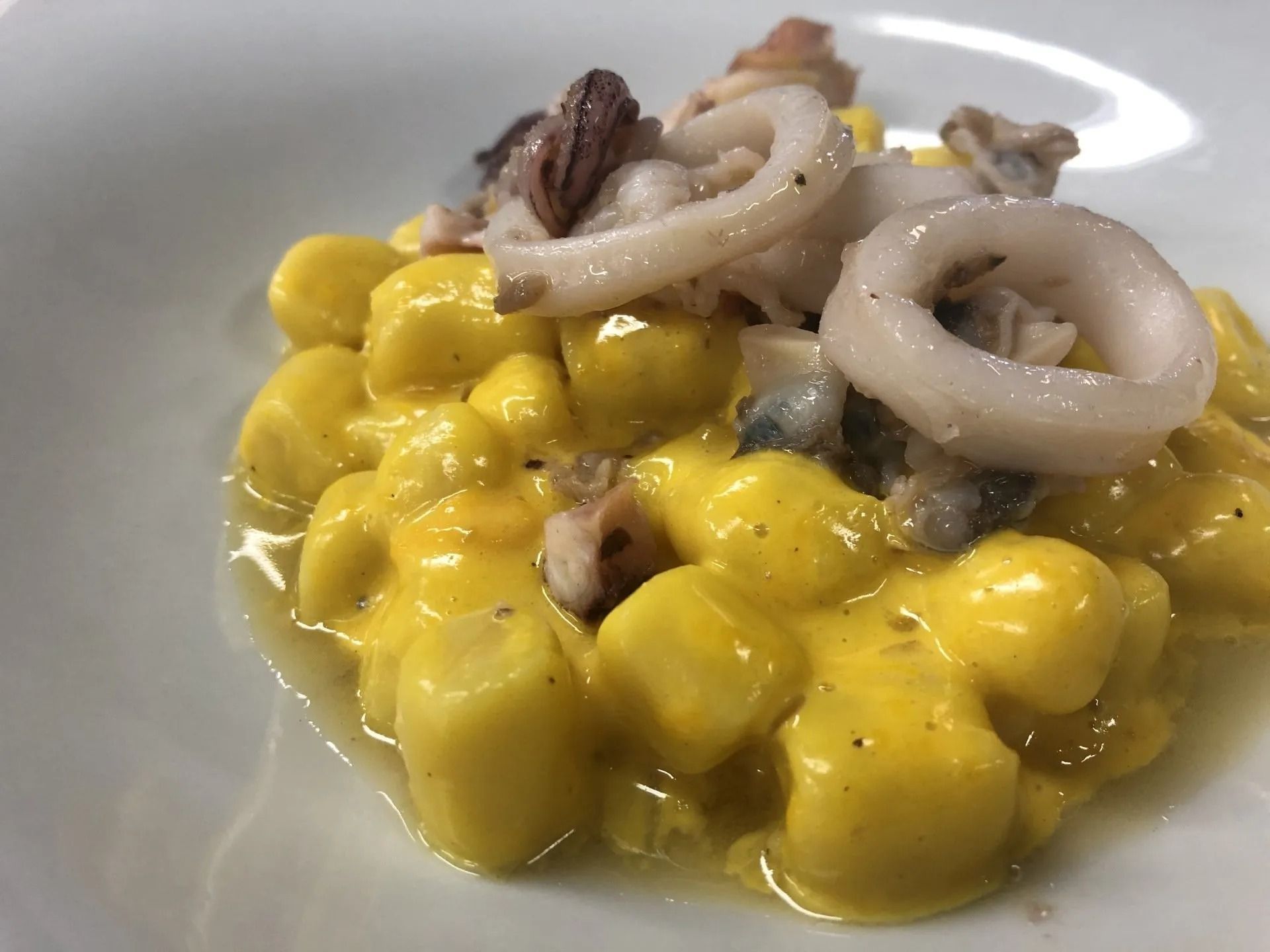 Un primo piano di un piatto di gnocchi e calamari su un tavolo.