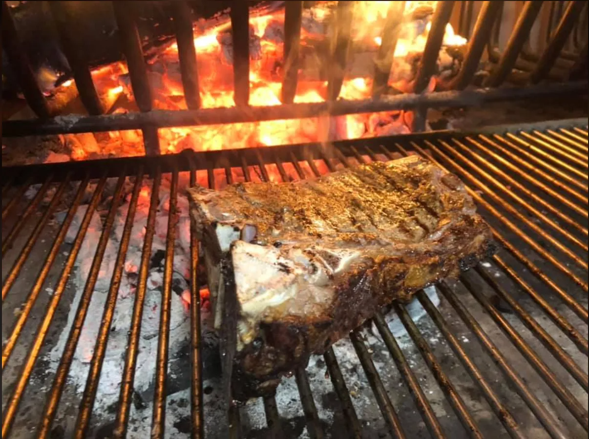 Un grosso pezzo di carne sta cuocendo su una griglia