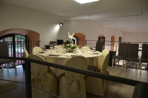 Una sala con tavoli e sedie allestita per un ricevimento di nozze