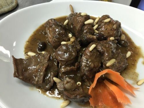 Un piatto bianco condito con ragù di carne, carote e pinoli