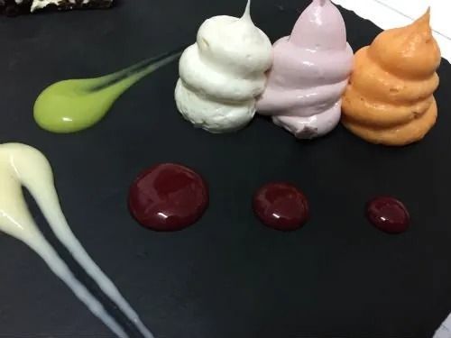 Un piatto nero ricoperto di glassa e salse di diversi colori