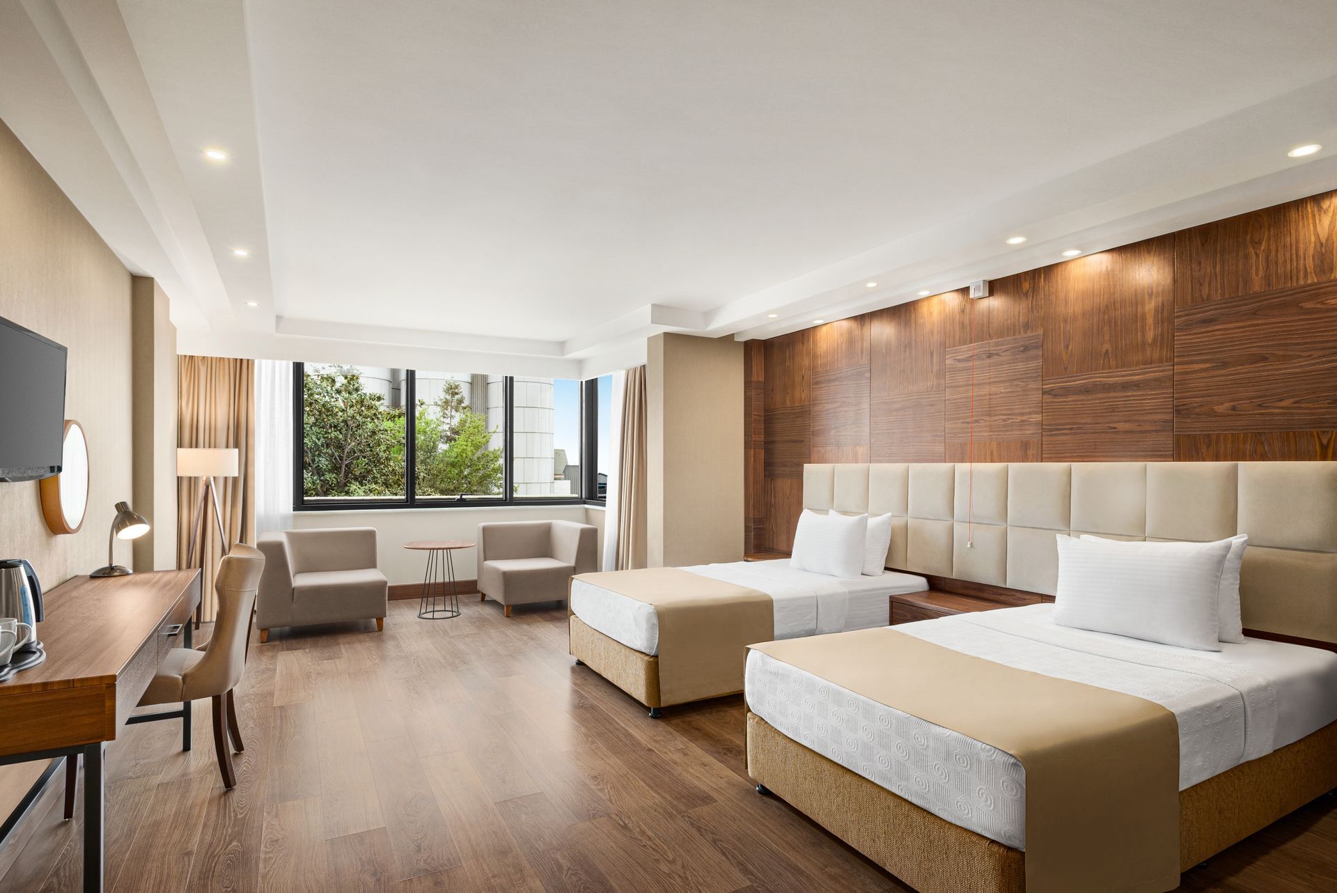 Ramada Plaza Samsun | İki yatak, kanepe, çalışma masası ve geniş pencereden manzaraya sahip, aydınlık ve modern otel odası.