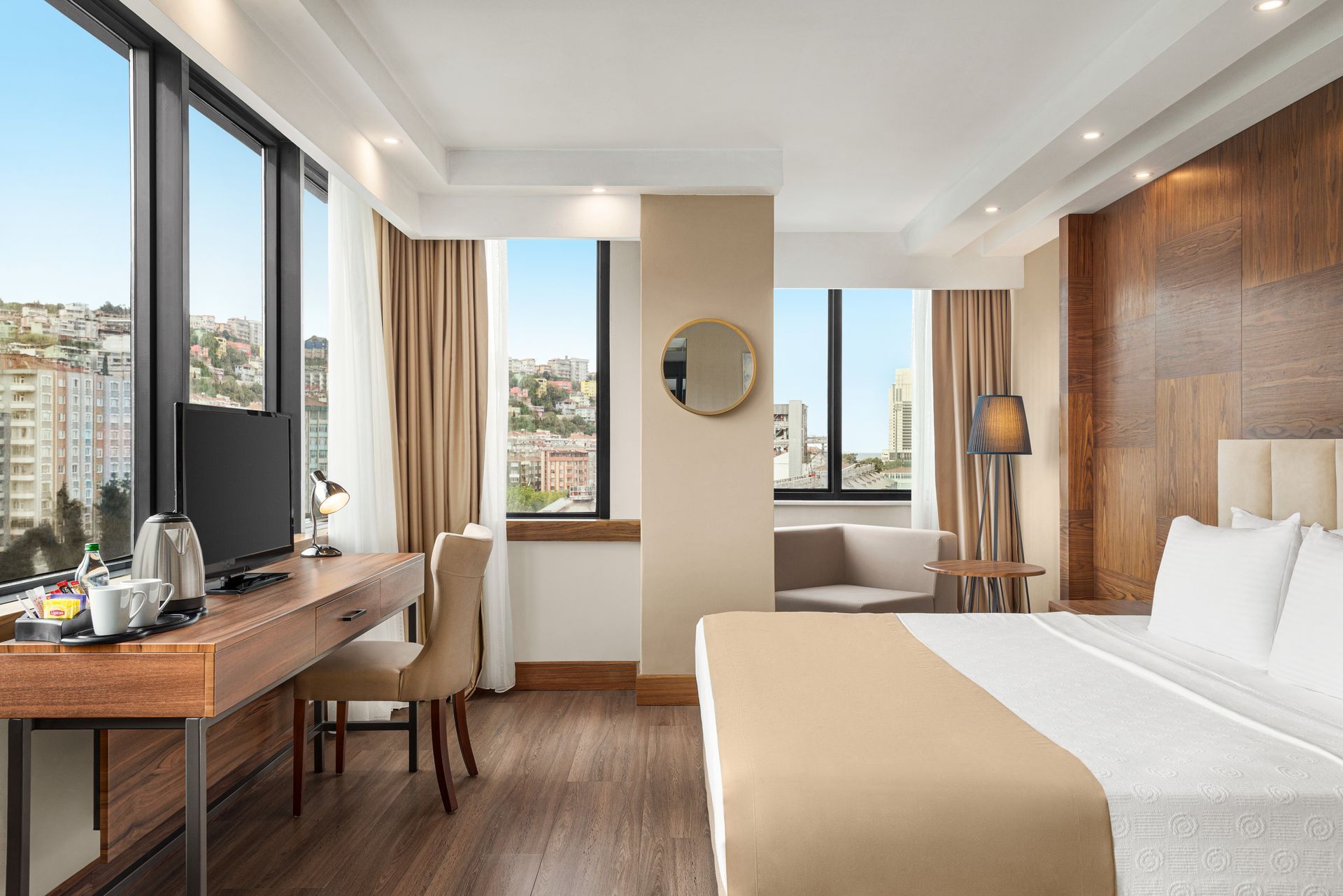 Ramada Plaza Samsun | Şehir manzarasına bakan geniş pencereleri, yatağı ve çalışma masası bulunan modern otel odası.