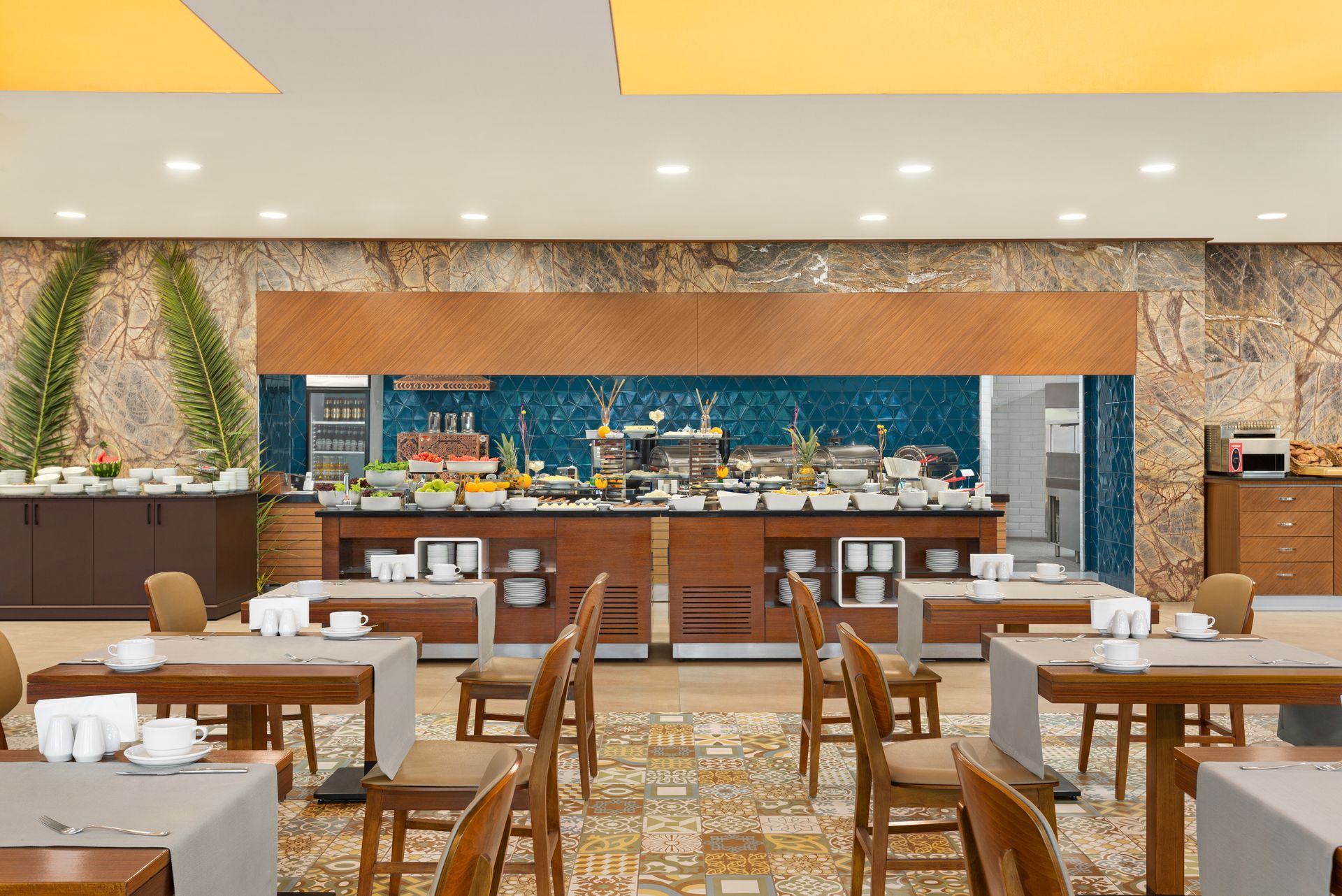 Ramada Plaza Samsun |  Boş masaları, kahverengi sandalyeleri ve mavi fayanslı büfe tezgahıyla modern bir otel restoranı.