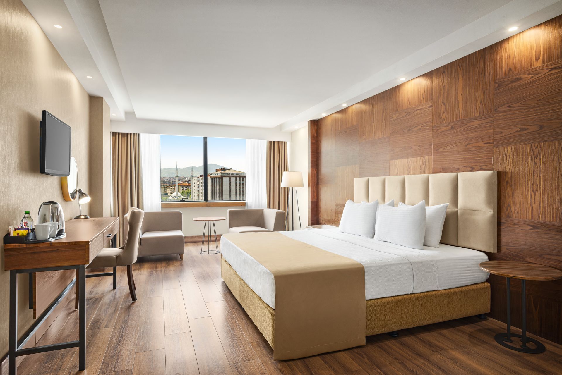 Ramada Plaza Samsun | Çift kişilik büyük yatak, çalışma masası, koltuk, ahşap zemin ve modern otel odası.