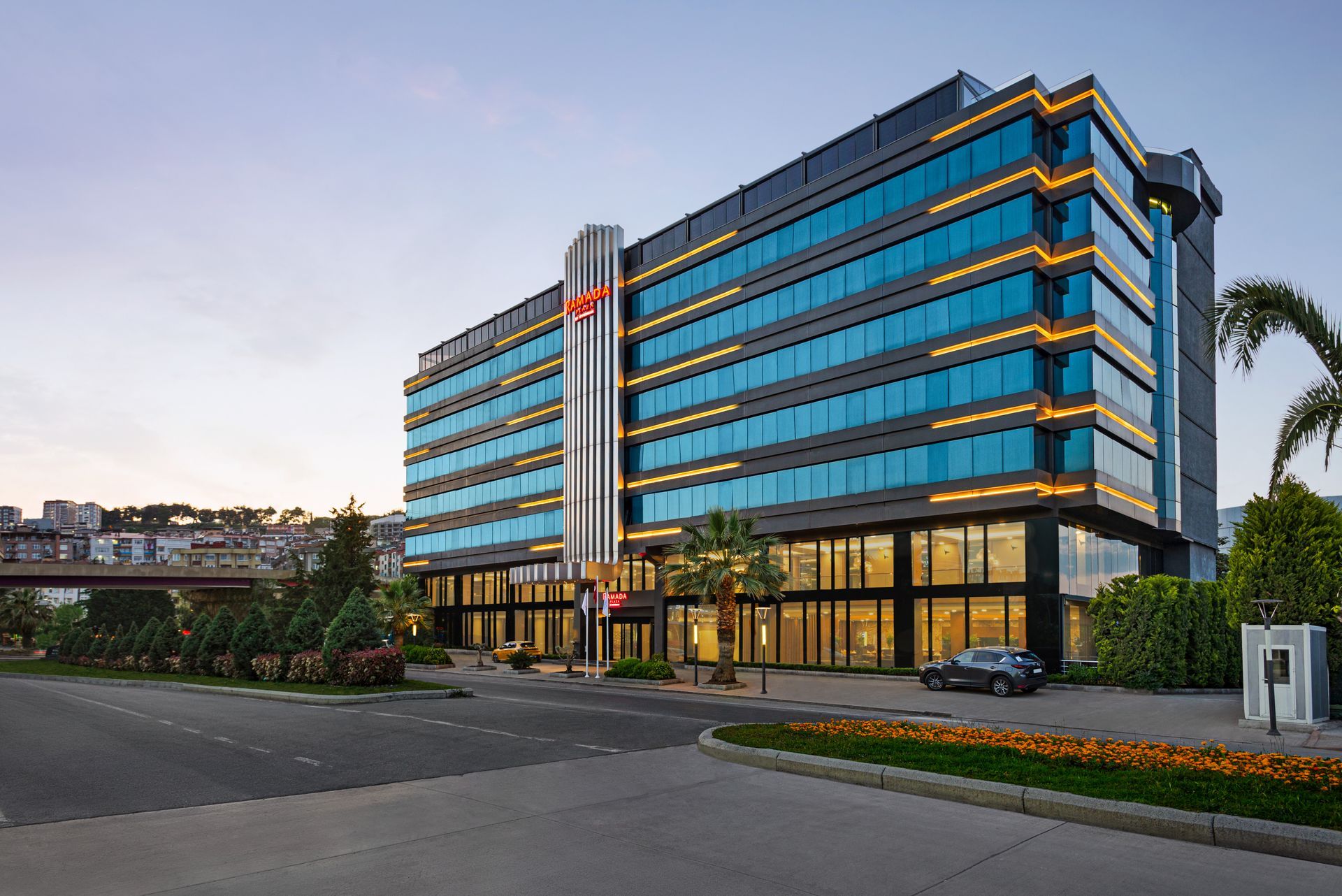 Ramada Plaza Samsun |  Gün batımında mavi tonlu camlara sahip modern cam otel binası.