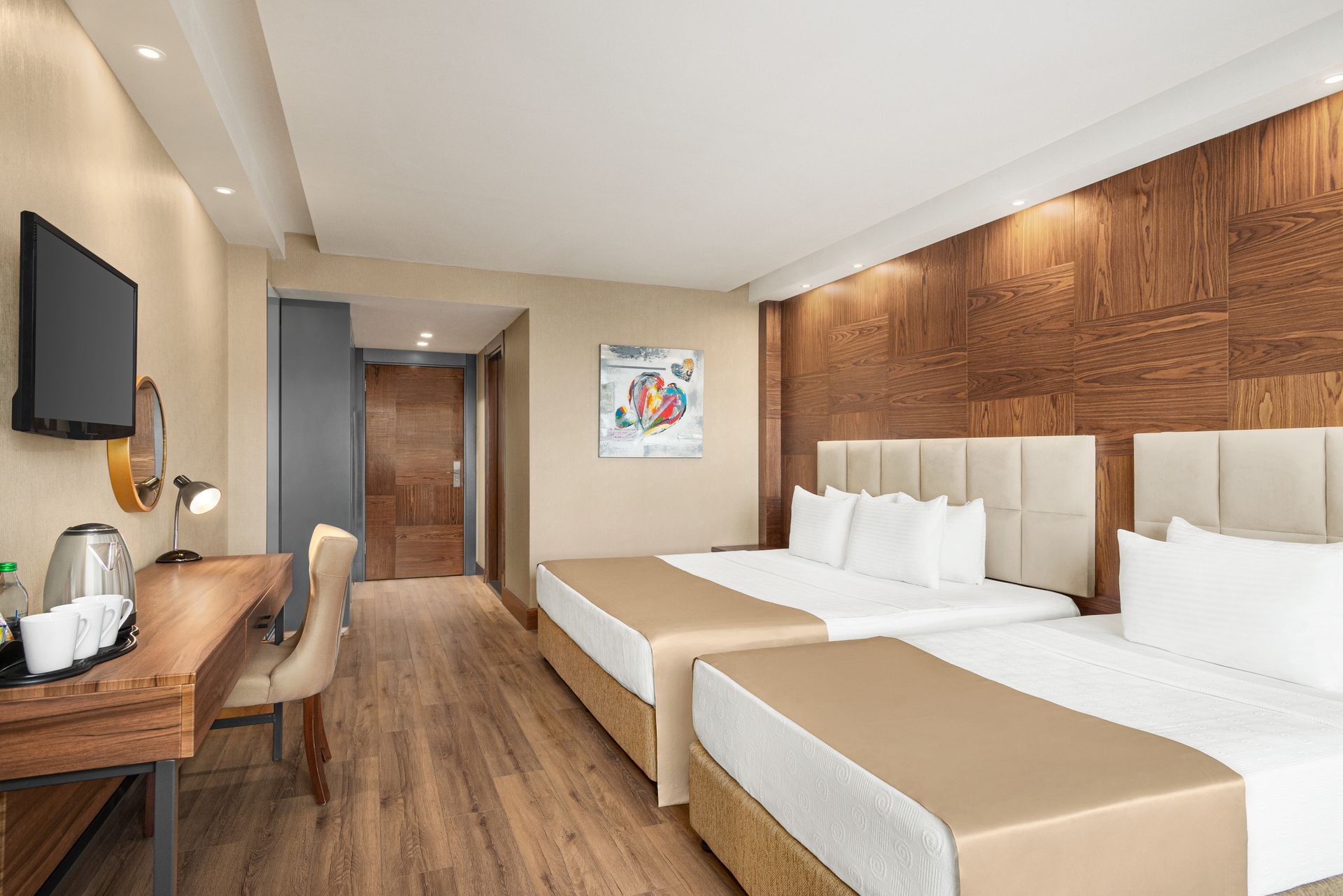 Ramada Plaza Samsun |  İki adet çift kişilik yatak, ahşap detaylı duvar, çalışma masası bulunan modern otel odası.