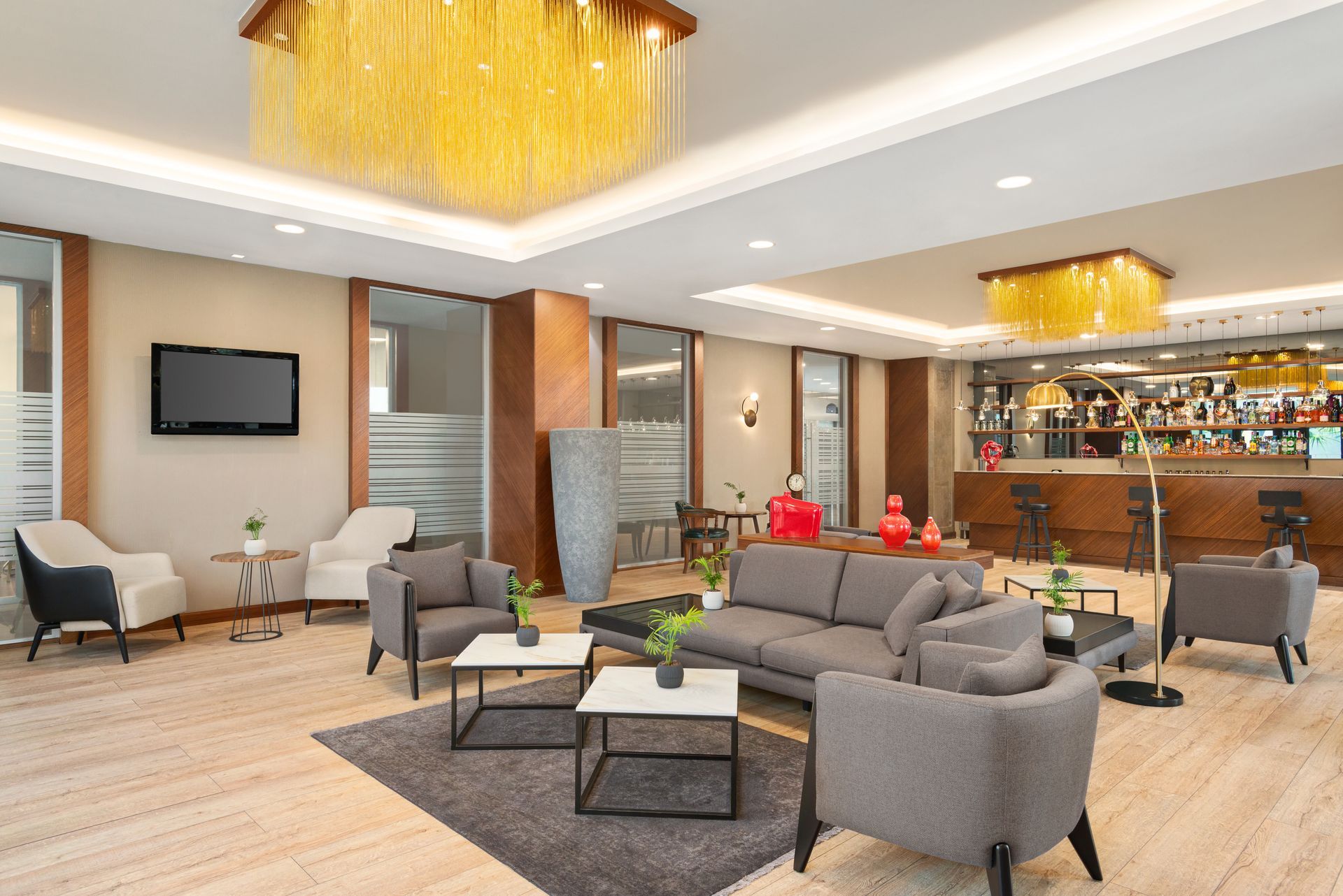 Ramada Plaza Samsun | Gri oturma grupları, sarı avizeler ve bar alanı bulunan modern otel lobisi.