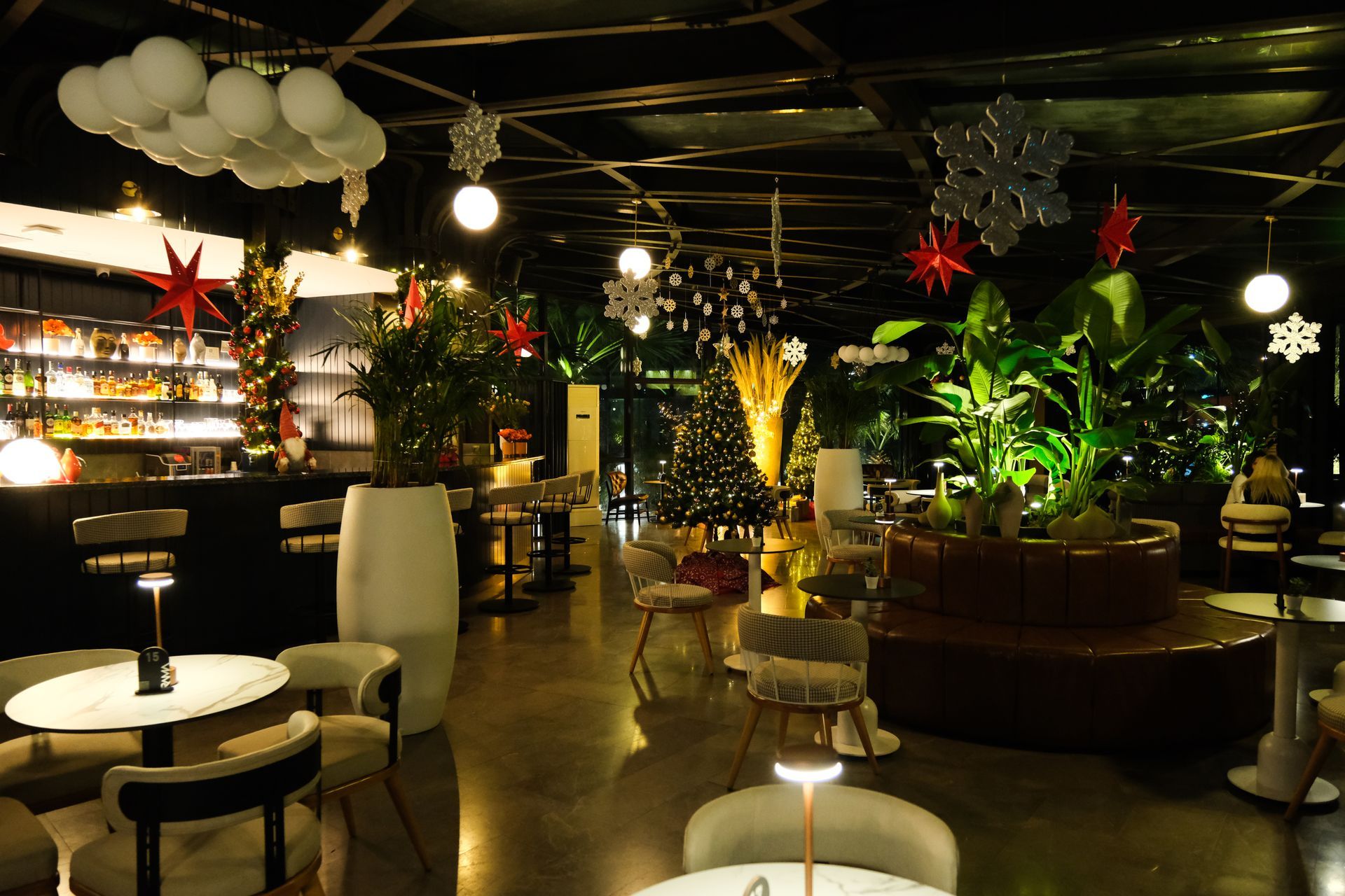 Ramada Plaza Samsun | Masalar, sandalyeler, asılı lambalar ve yemyeşil bitkilerle döşenmiş, loş ışıklı modern bir salon.