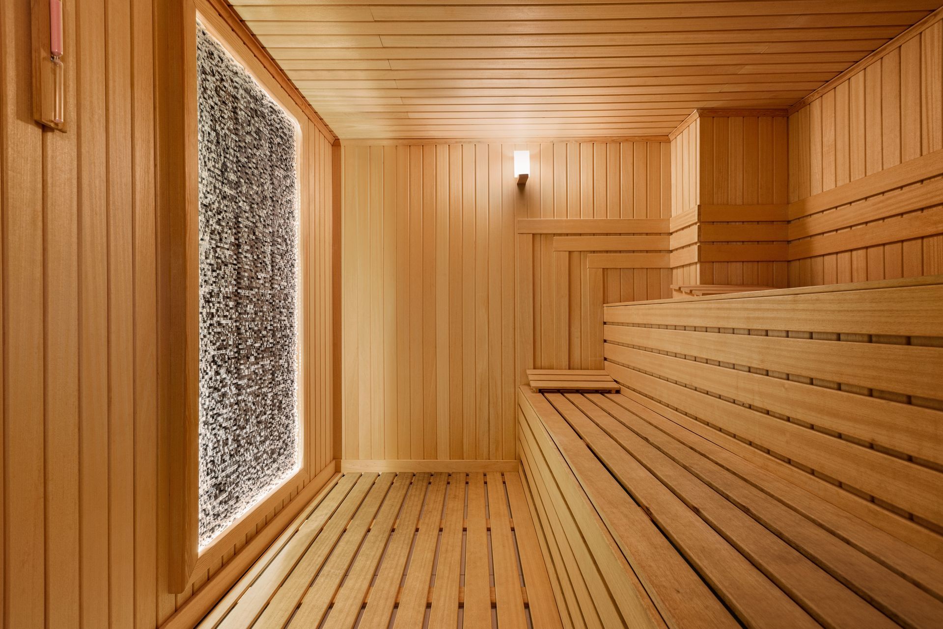 Ramada Plaza Samsun |  Ahşap panelli sauna iç mekanı, oturma bankları ve buzlu camlı pencere paneli ile donatılmıştır.