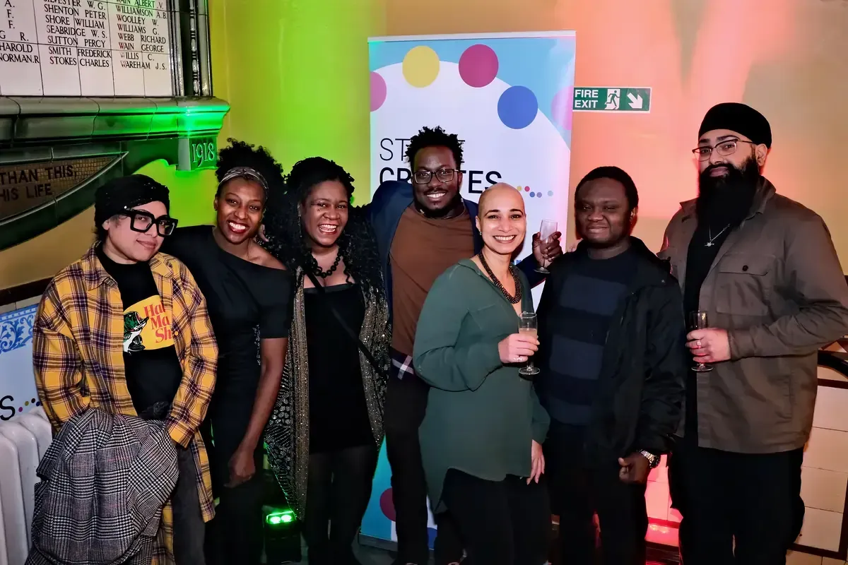 Group of people smiling and posing for a photo indoors at an event, in front of a banner.