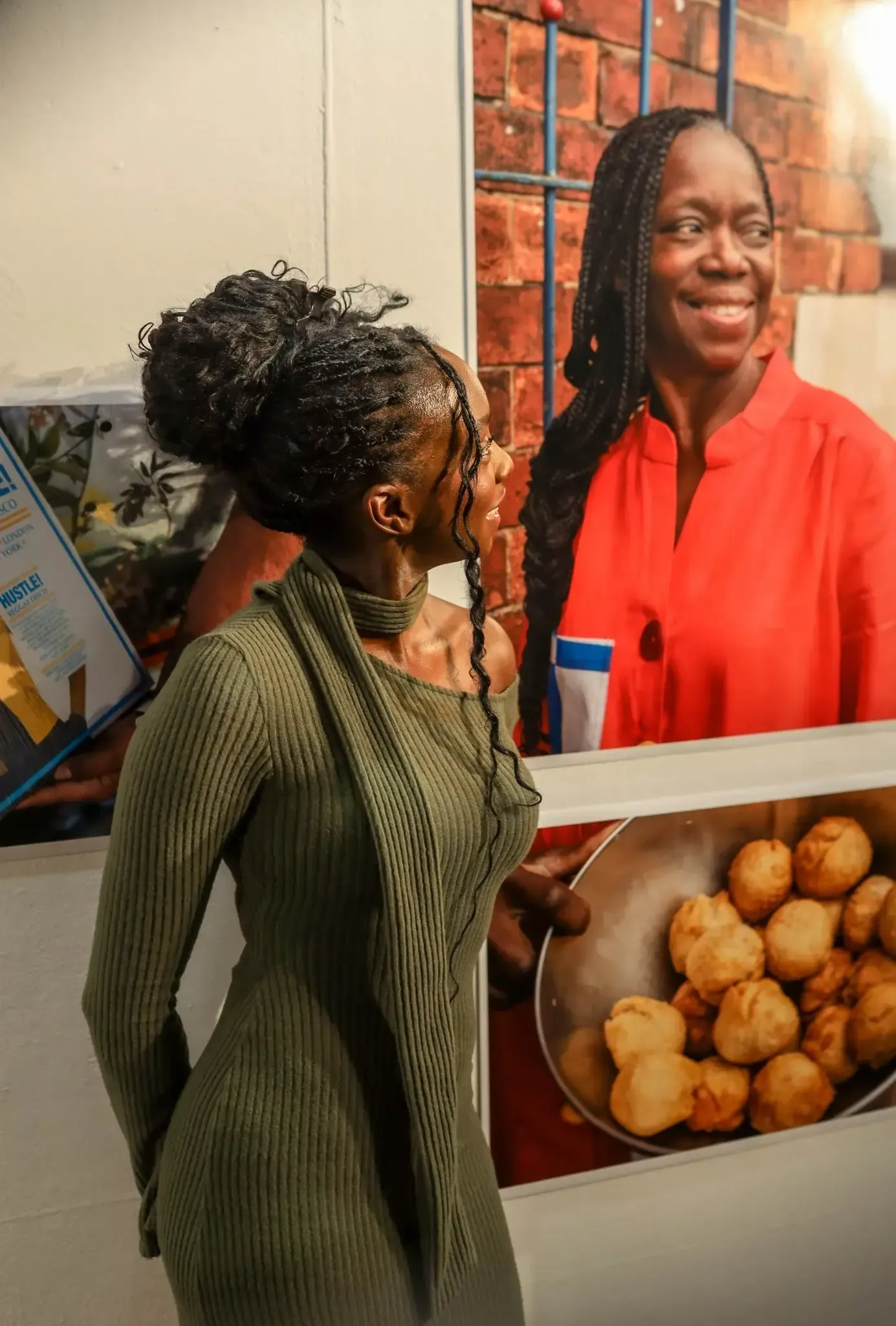 Woman in green dress, looking at a photograph of a woman holding fried dough in a restaurant.