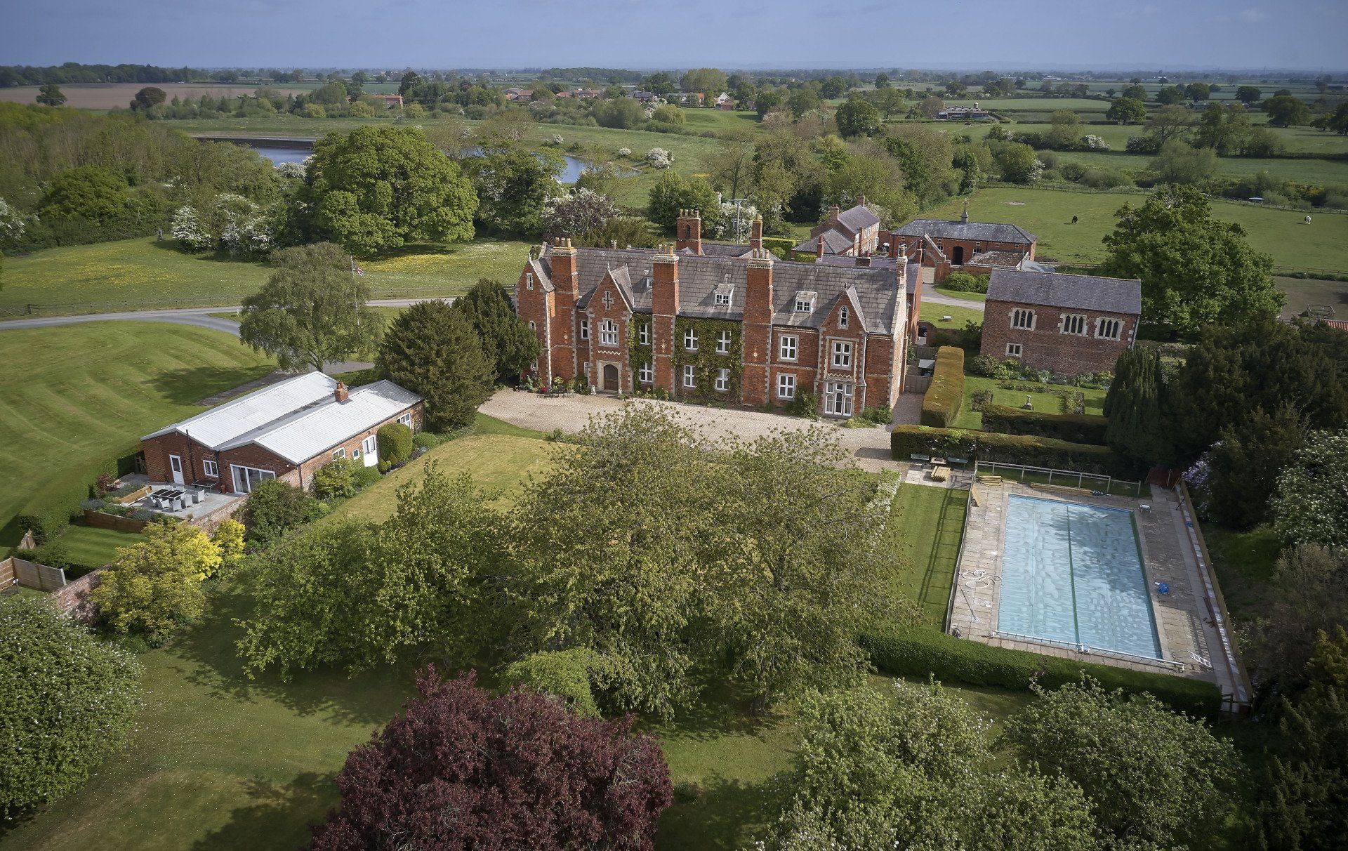 An aerial view of a large house surrounded by trees and a swimming pool.